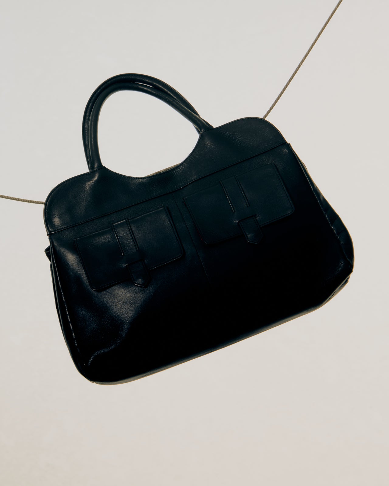 Black Alexander McQueen handbag on a light gray tiled floor