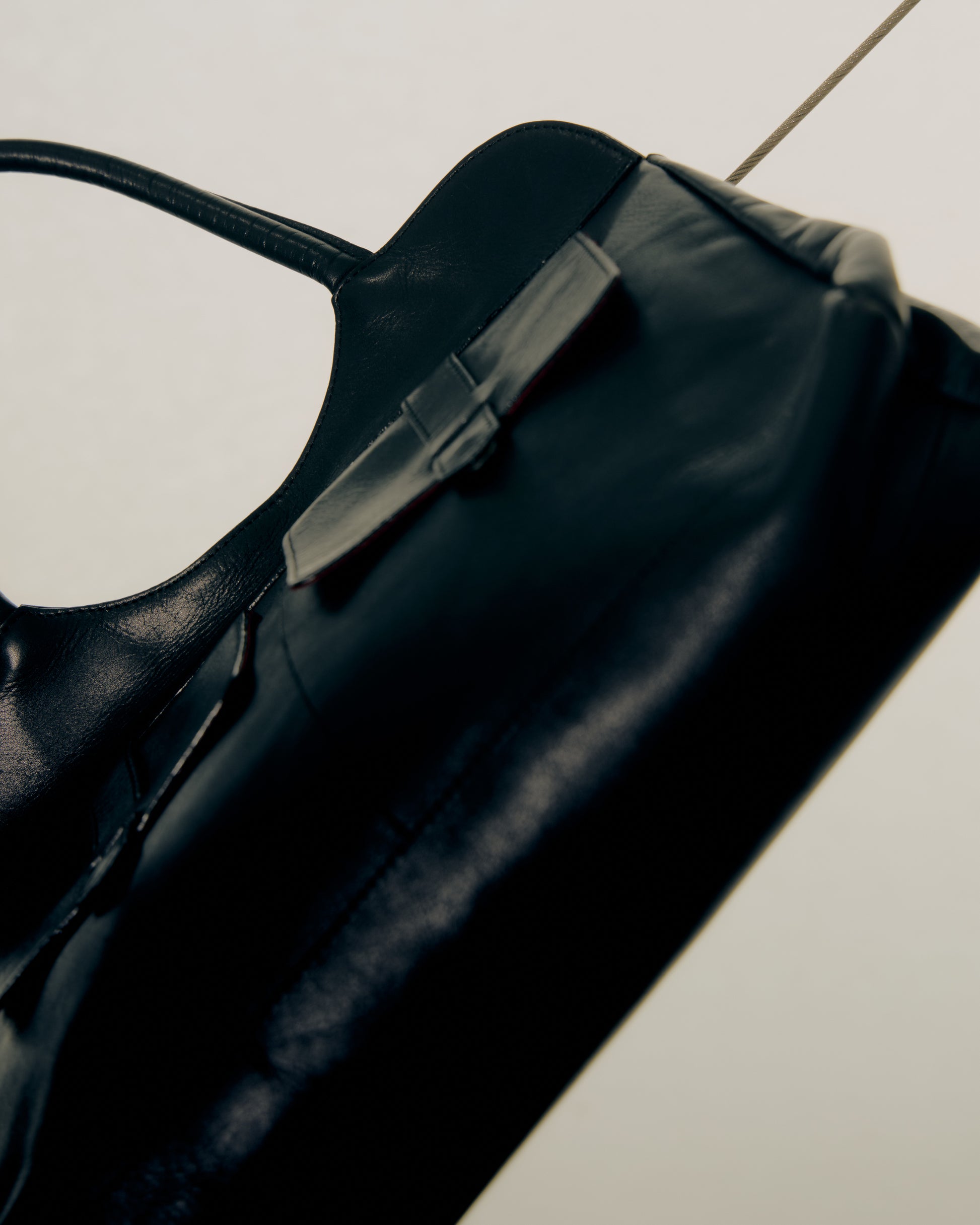 Close-up of a black leather Alexander McQueen bag on a light gray floor.