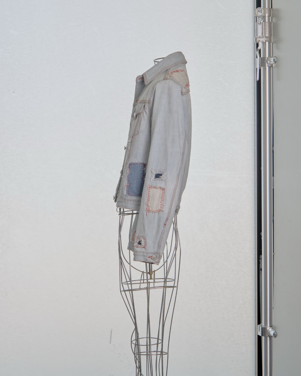 Denim Alexander McQueen jacket on a wire mannequin against a white wall