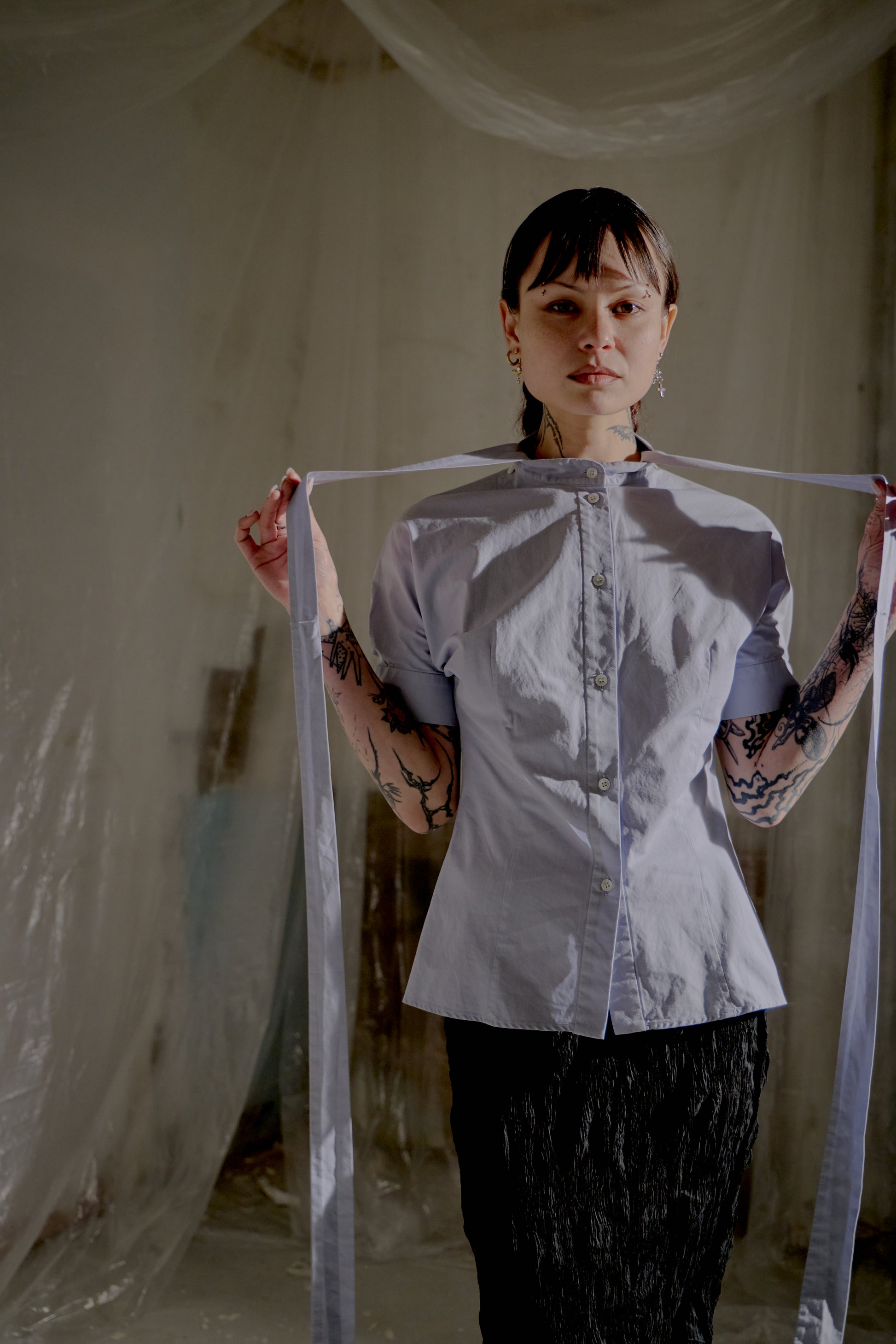 Person holding a ribbon from an Alexander McQueen shirt in a dimly lit room