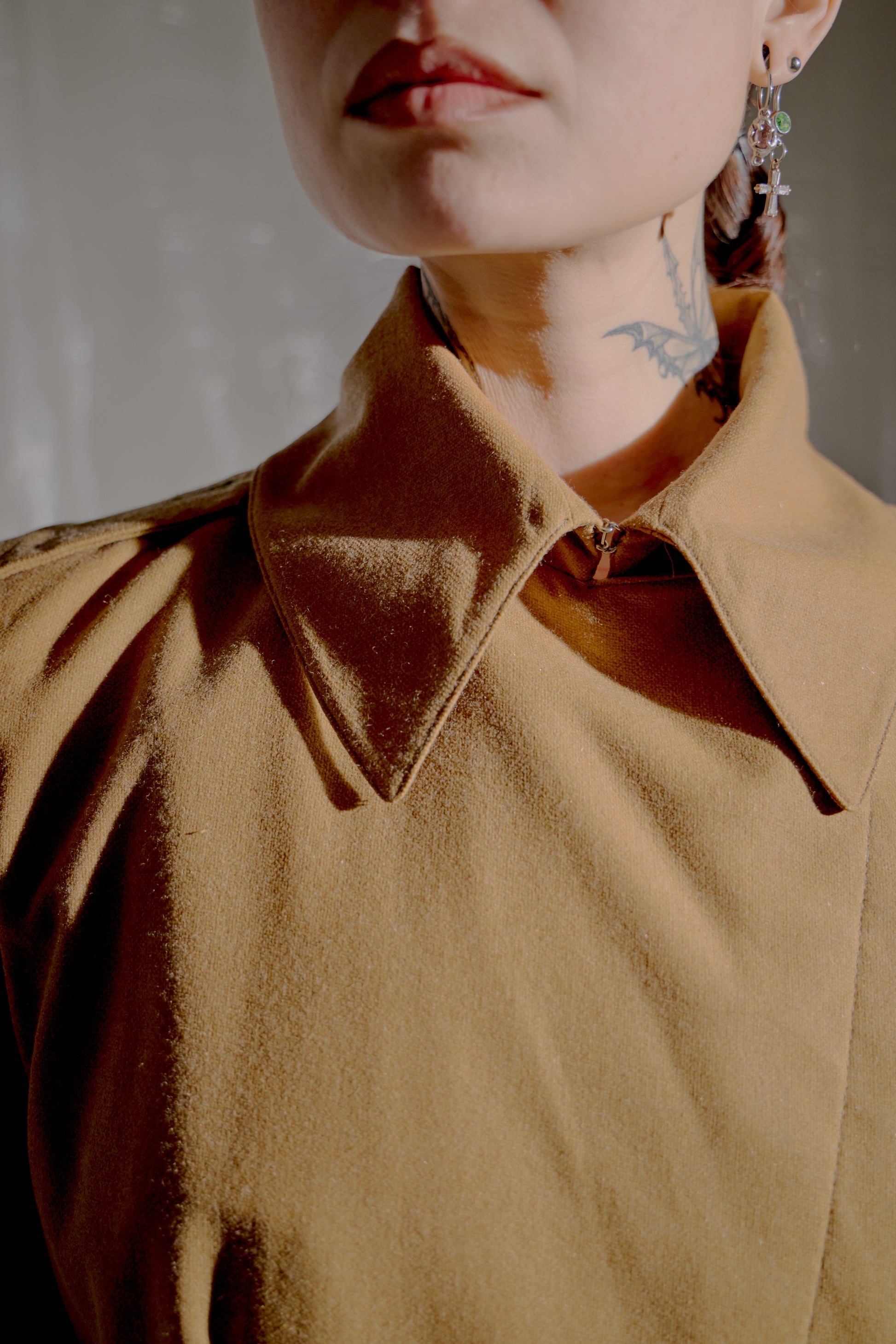 Close-up of a person Alexander McQueen wearing a brown jacket with a collar.