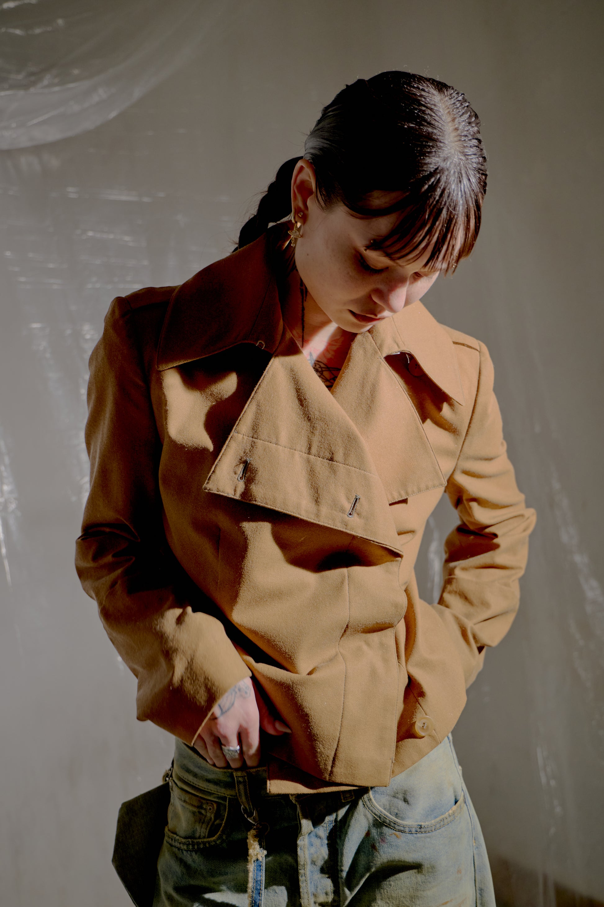 Person wearing a brown Alexander McQueen jacket with a plain background