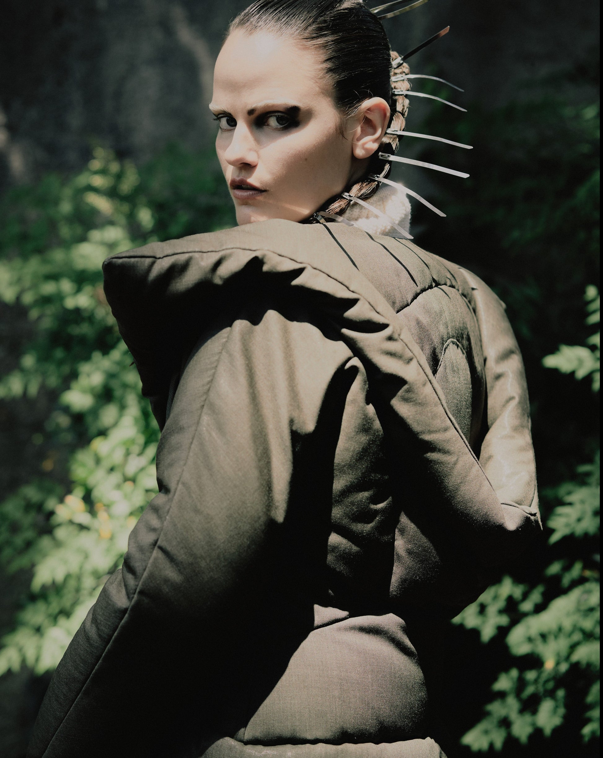 A person wearing a green duvet puffer jacket with a hood, reminiscent of Alexander Mcqueen's FW 1999 'The Overlook' Collection inspired by Stanley Kubrick's film 'The Shining'.