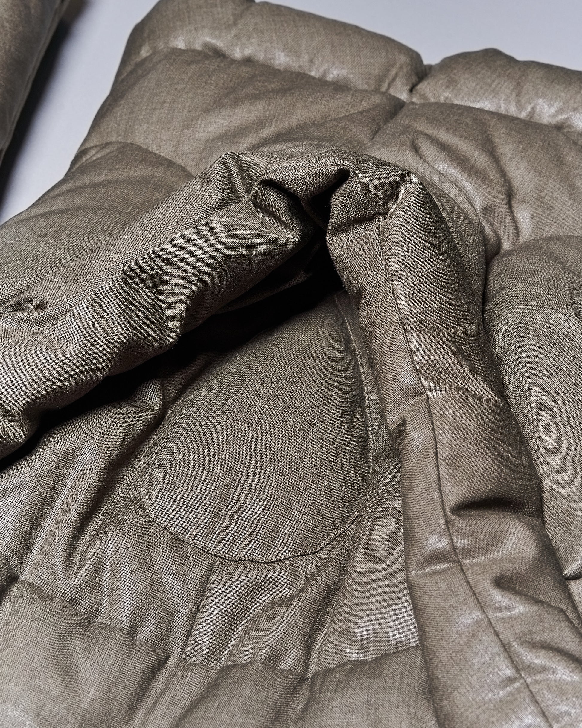 Close-up of a textured, padded olive green Alexander McQueen fabric with quilted stitching. 