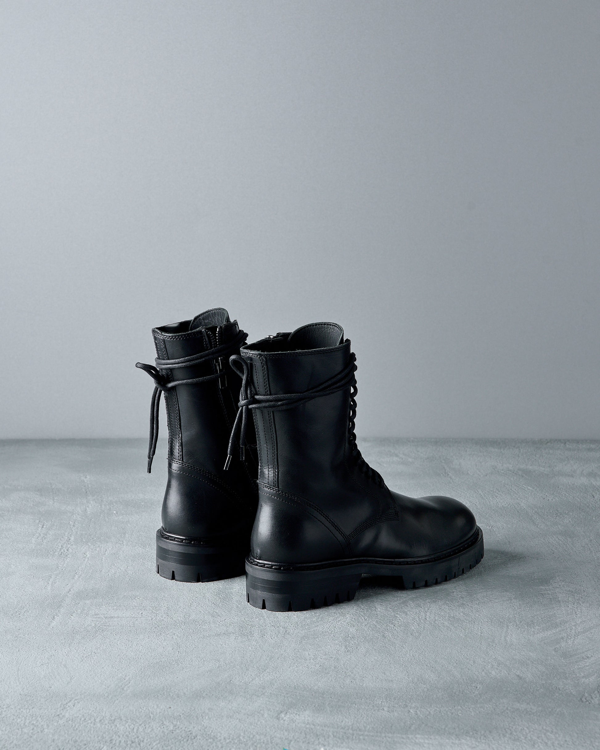 Pair of black leather Ann Demeulemeester  boots on a gray surface with a neutral background
