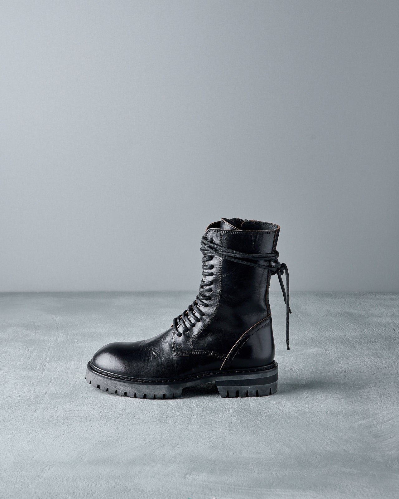 Black leather Ann Demeulemeester boot on a grey background
