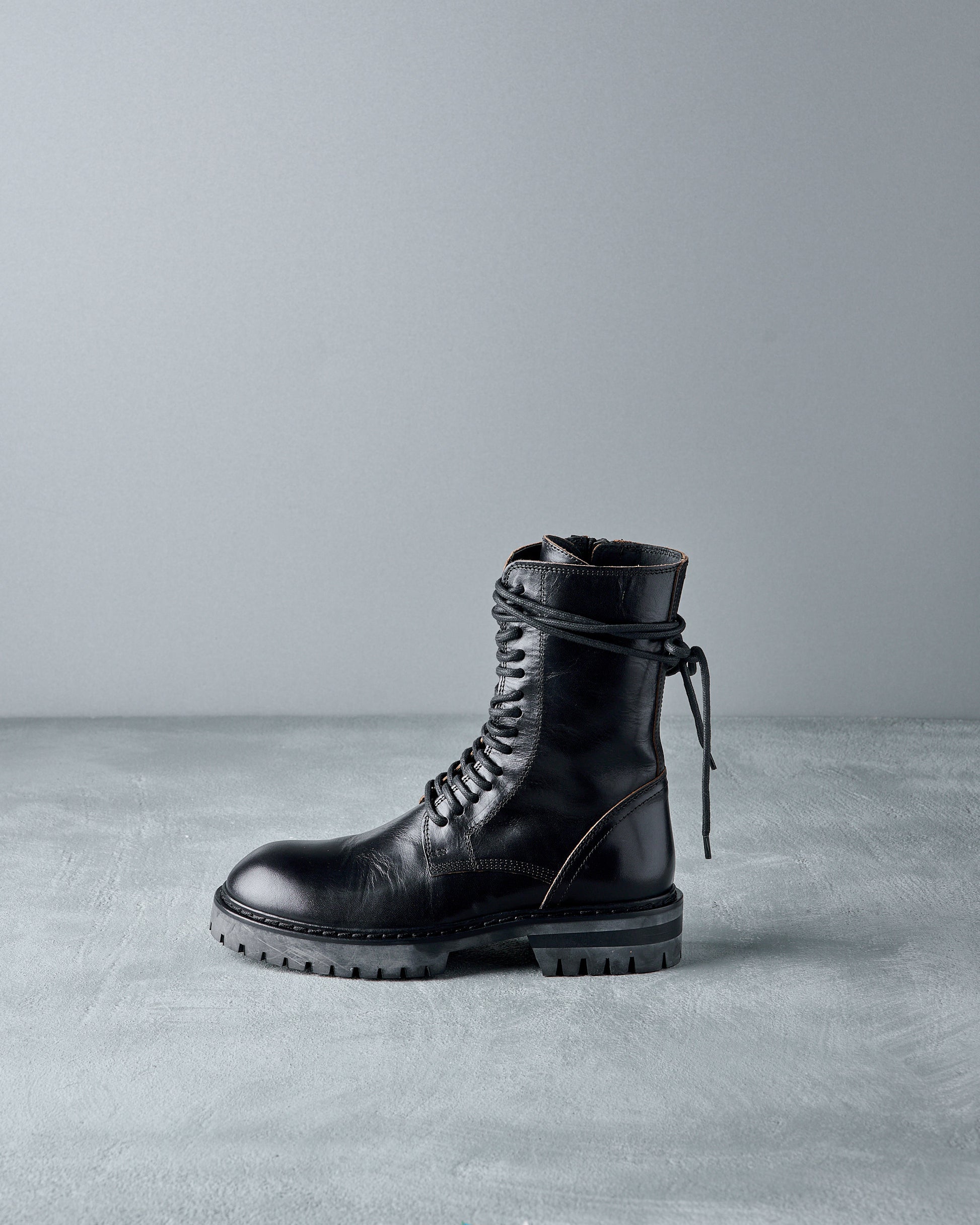 Black leather Ann Demeulemeester boot on a grey background