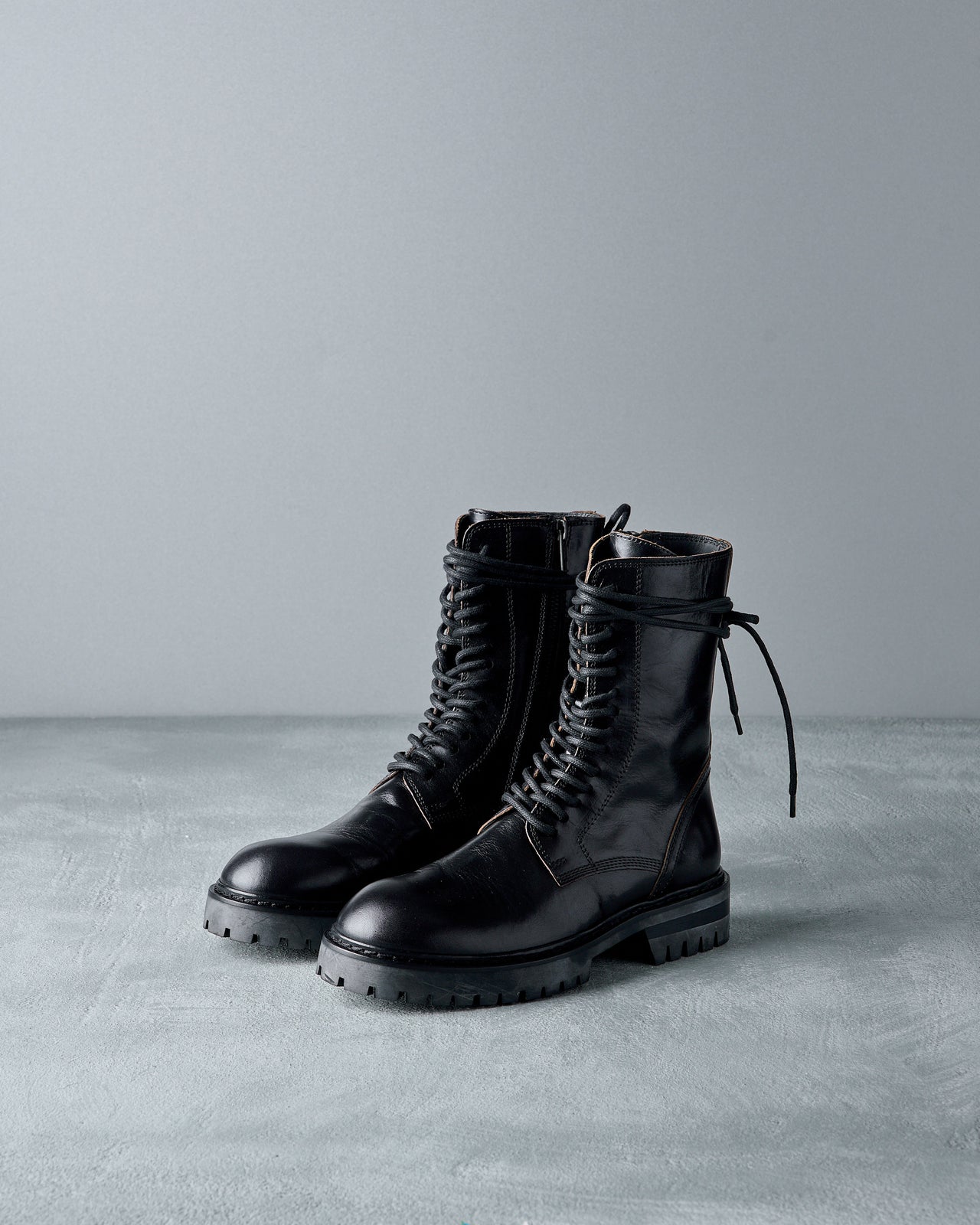 Black leather Ann Demeulemeester boot on a grey background