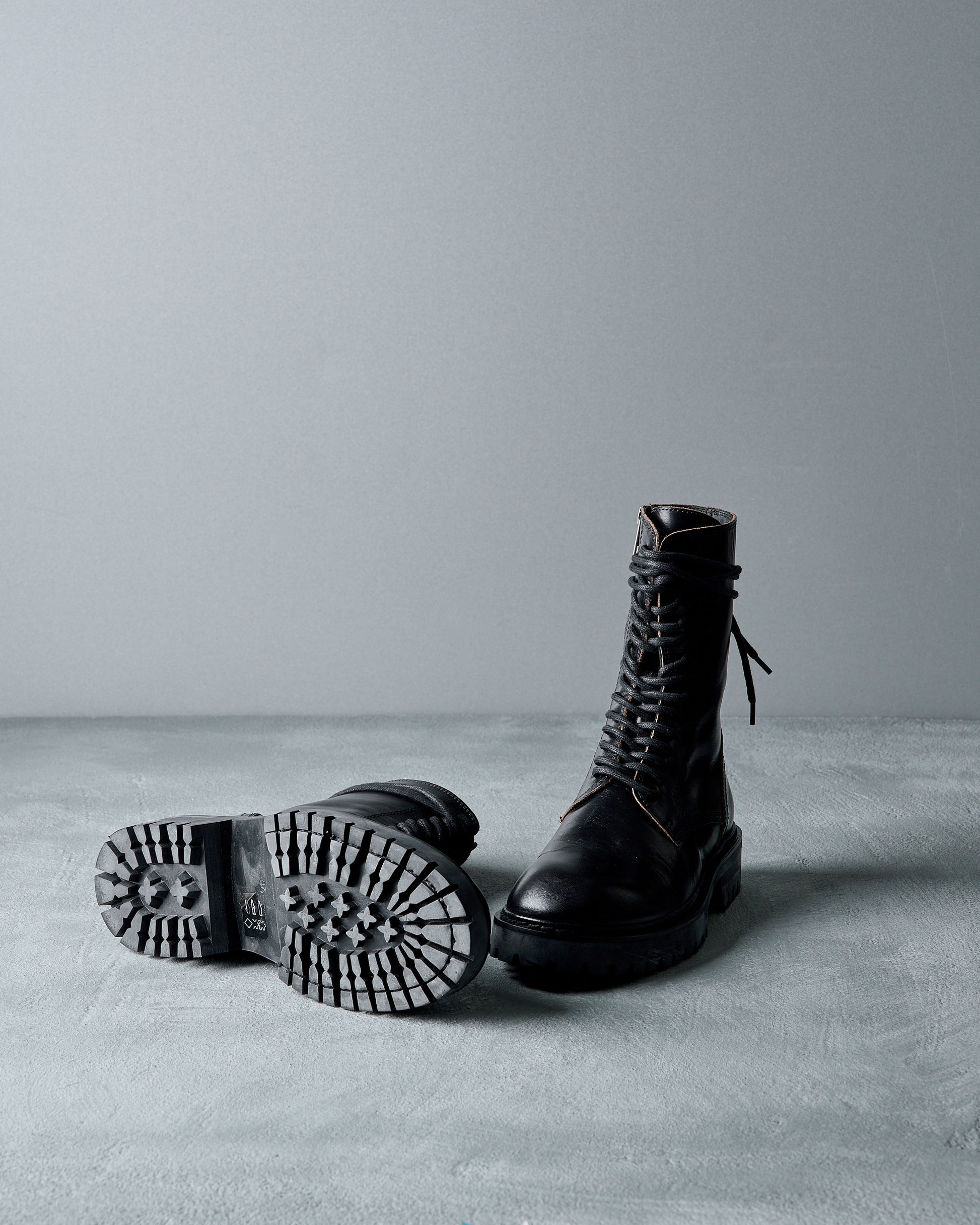 Pair of black leather Ann Demeulemeester  boots on a gray surface with a neutral background