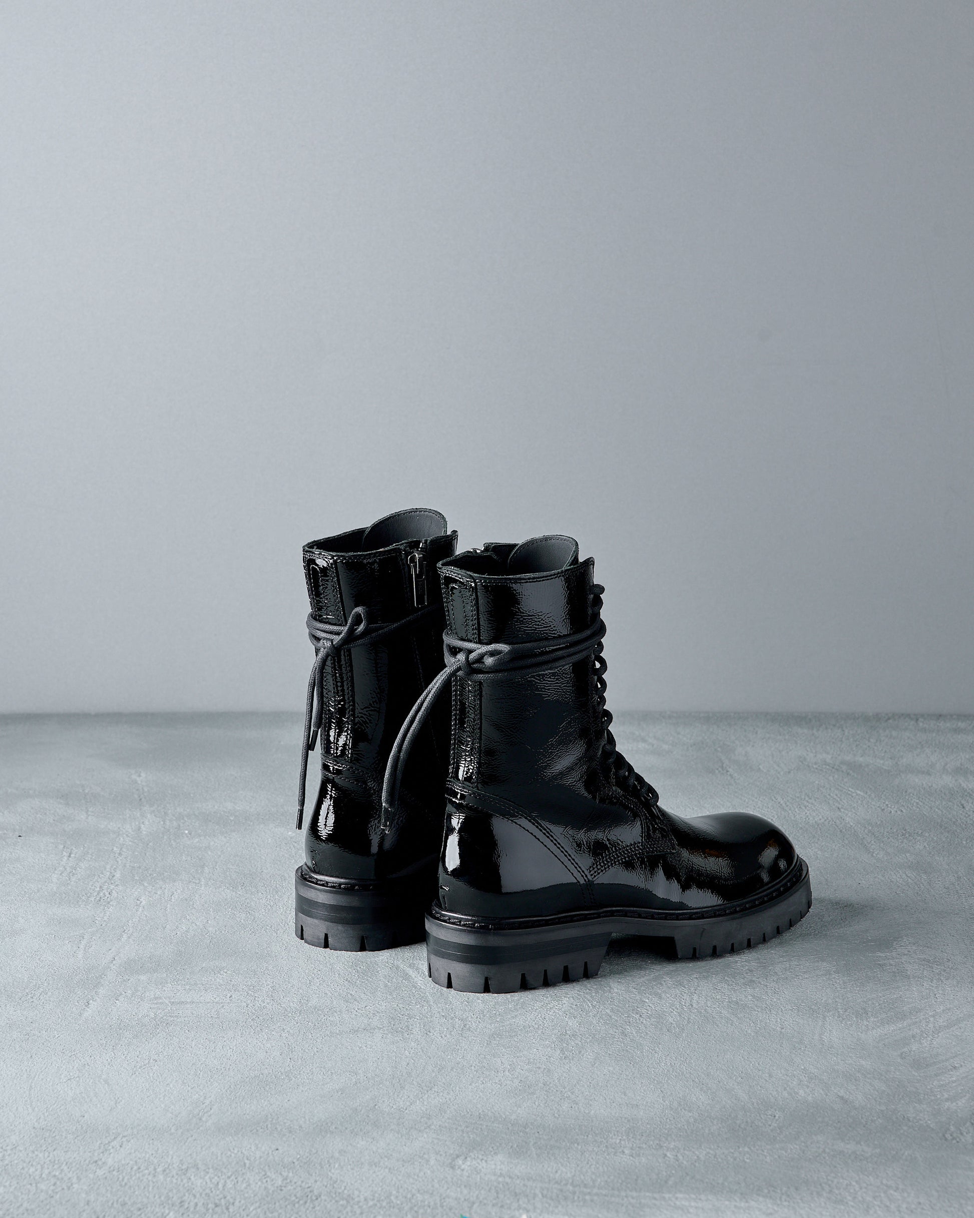 Black leather Ann Demeulemeester  boots on a gray surface with a neutral background