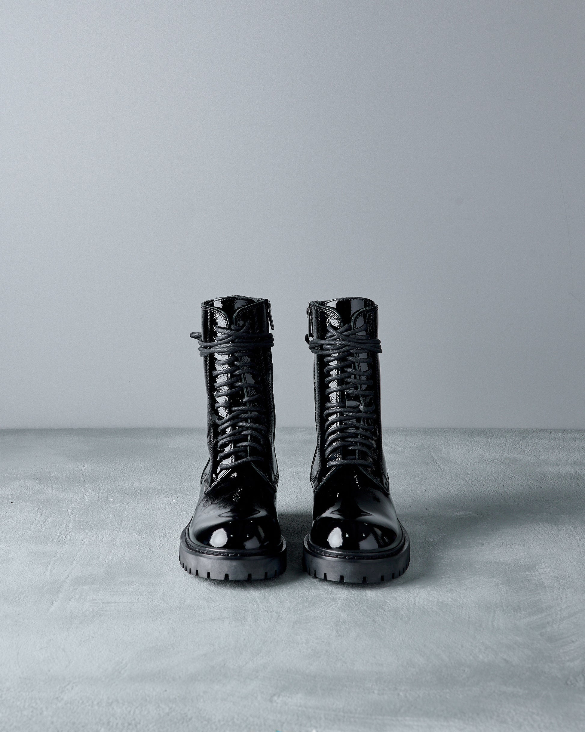 Pair of black leather Ann Demeulemeester  boots on a gray surface with a gray background