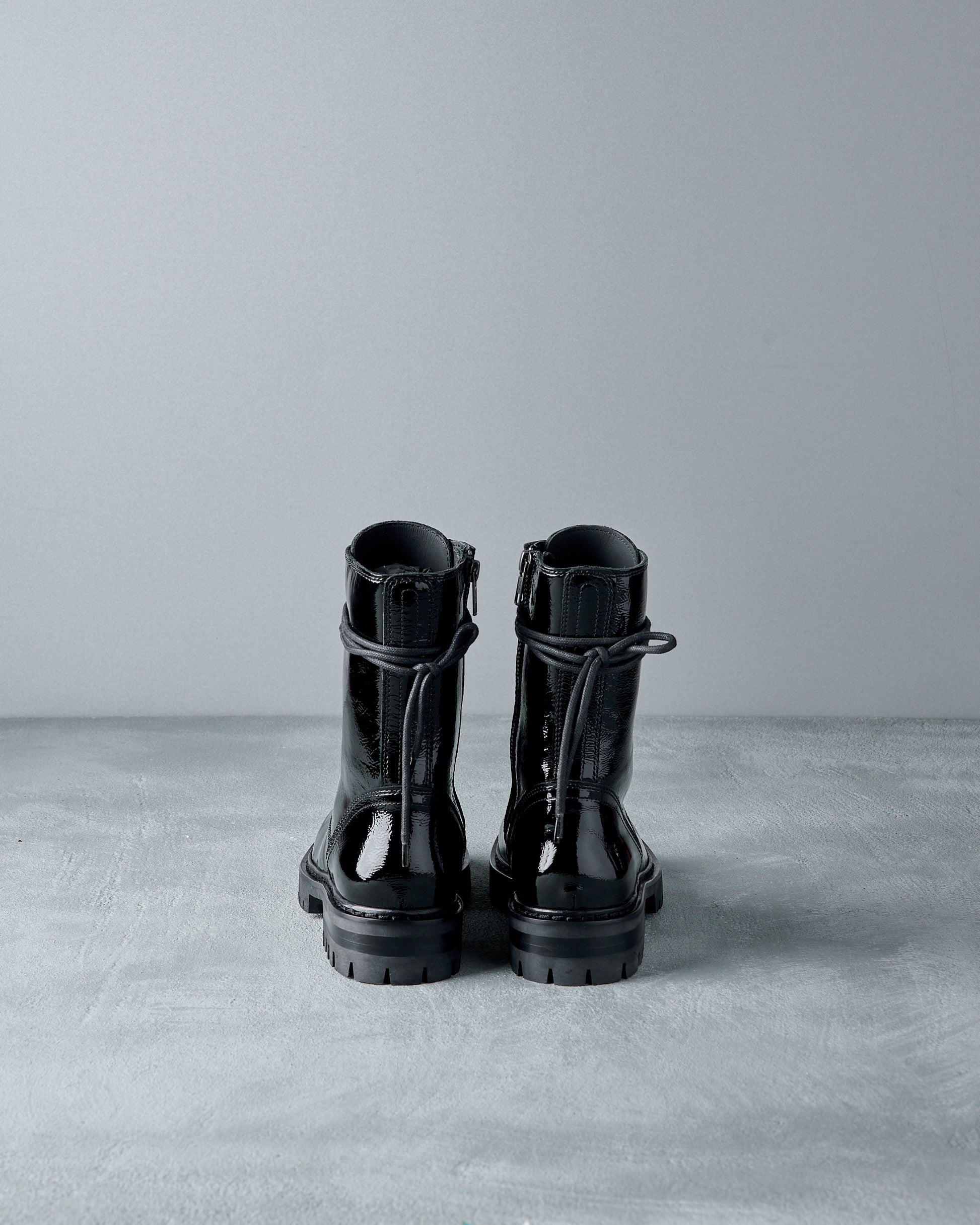 Pair of black leather Ann Demeulemeester  boots on a gray surface with a light gray background
