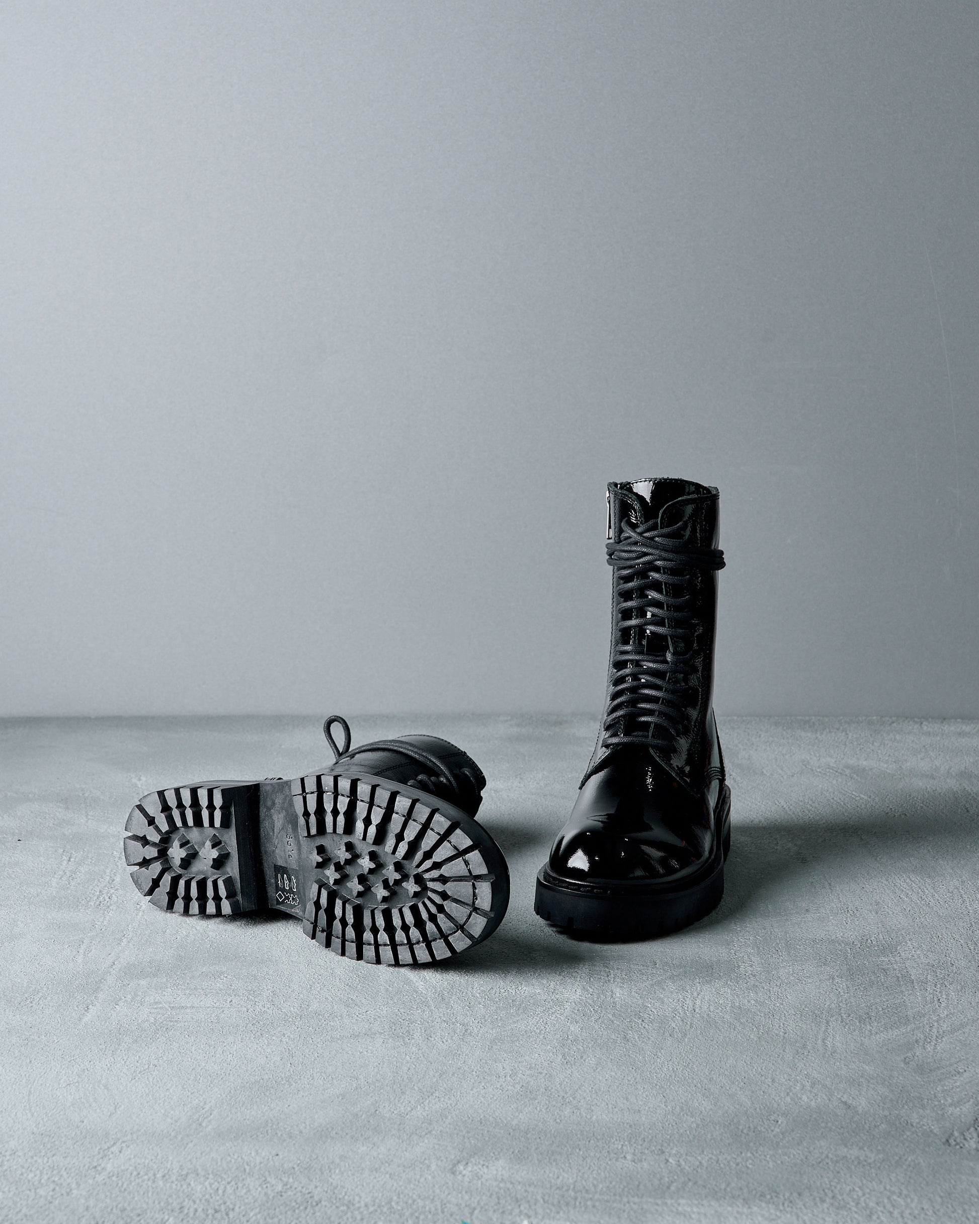 Black leather Ann Demeulemeester boots on a gray surface with a neutral background