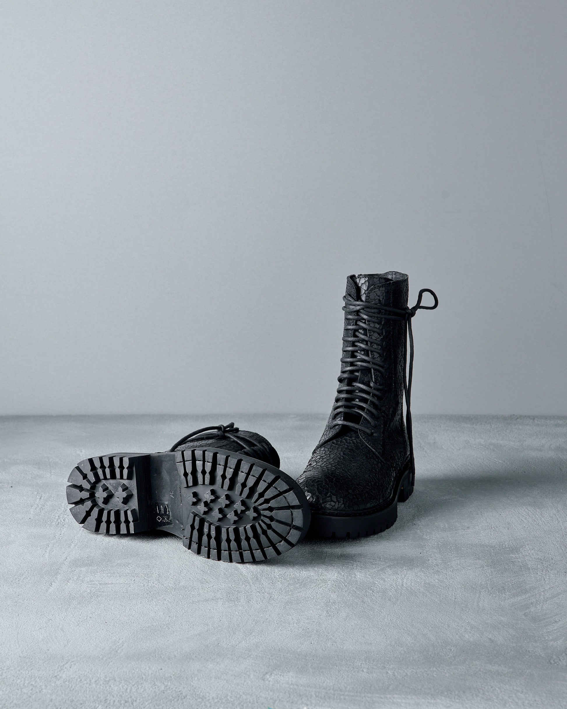 Pair of black leather Ann Demeulemeester  boots on a gray surface with a light gray background