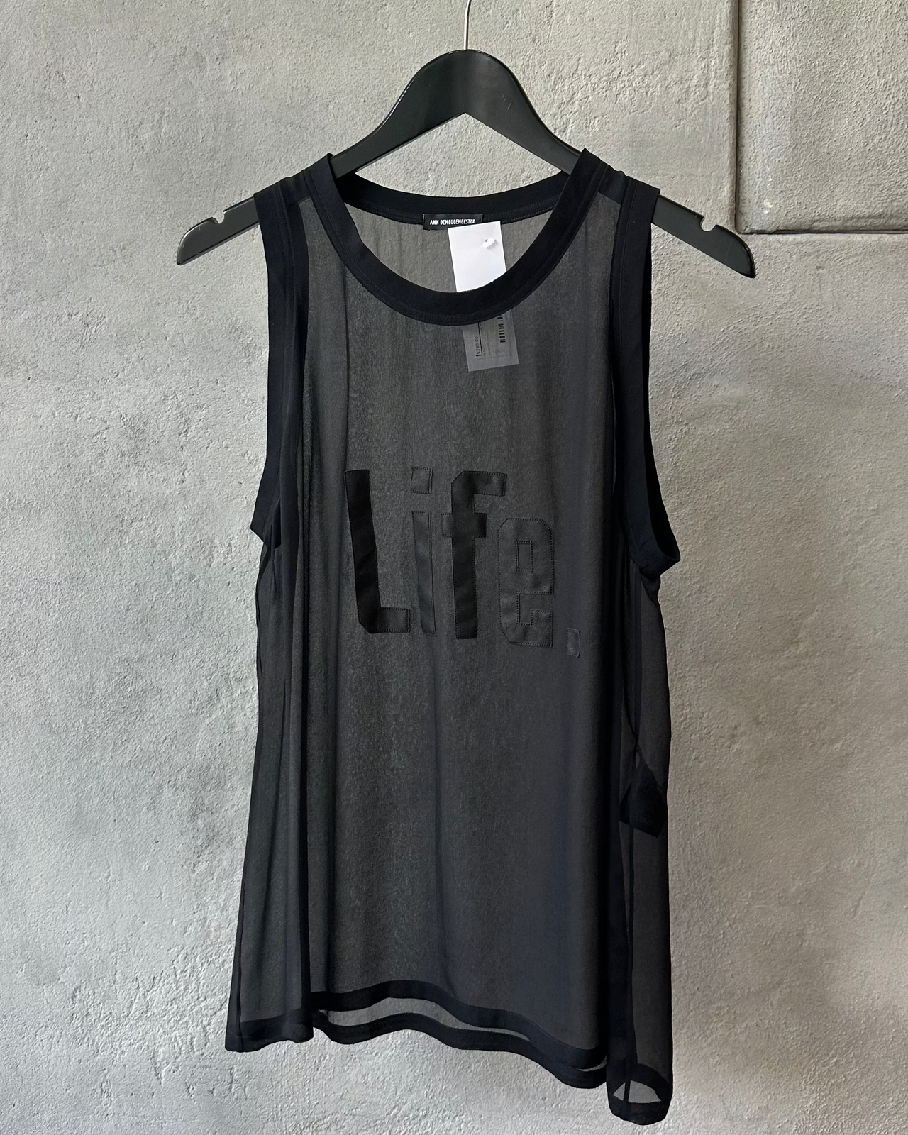 Model wearing a black Ann Demeulemeester shirt with 'Life.' printed on it at a fashion show.