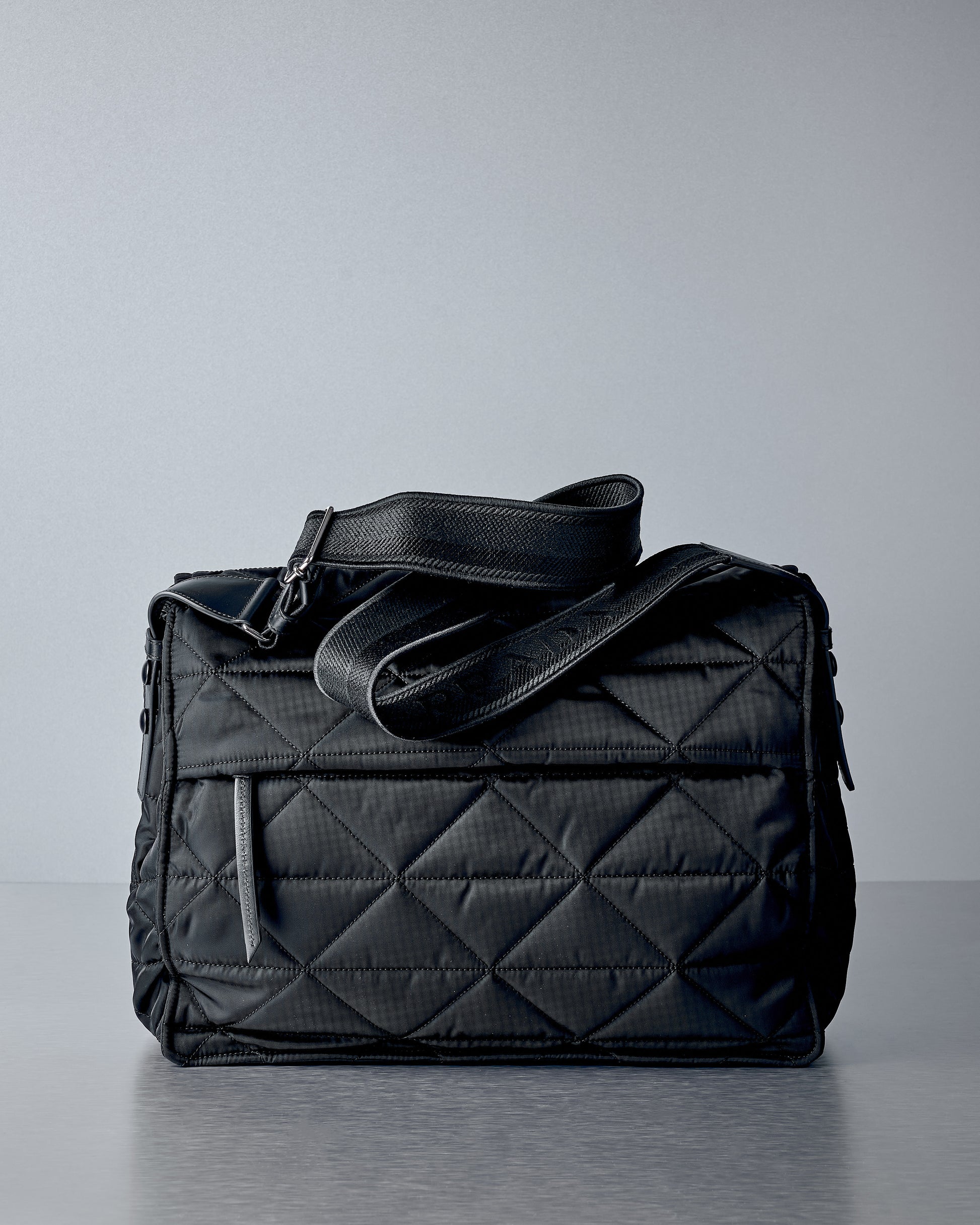 Black quilted Prada handbag on a grey background