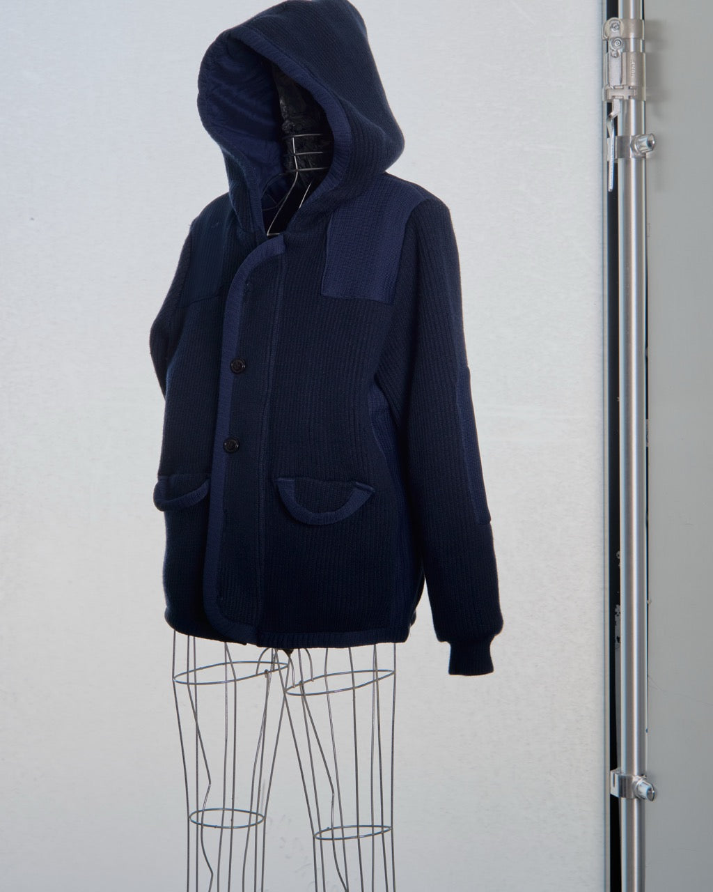 Navy blue hooded Balenciaga knit coat on a mannequin against a white background