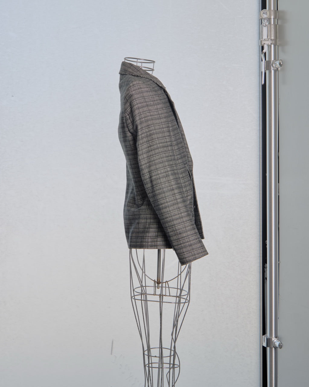 Gray checkered Balenciaga blazer on a mannequin against a light gray background