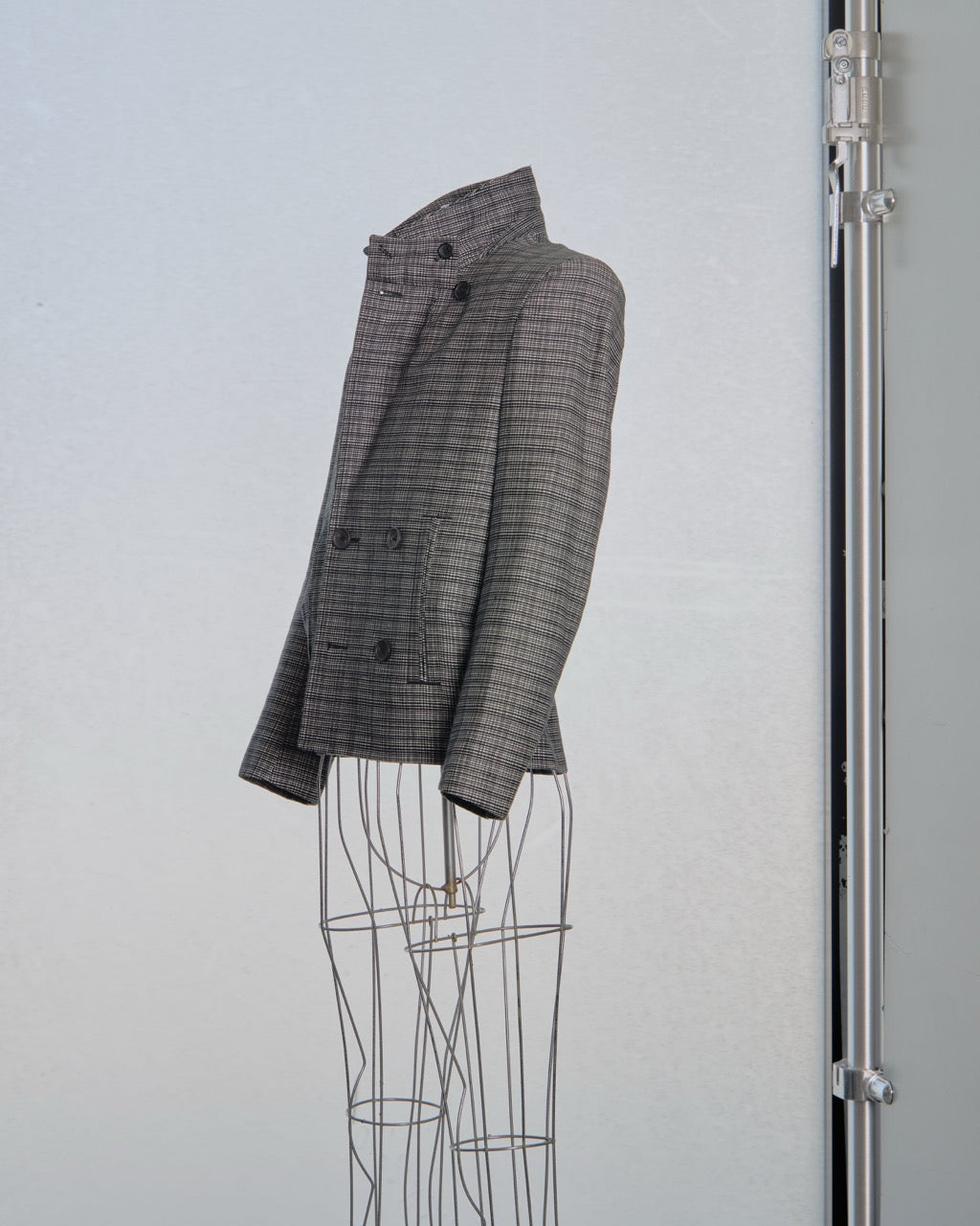 Gray checkered Balenciaga blazer on a mannequin against a light gray background