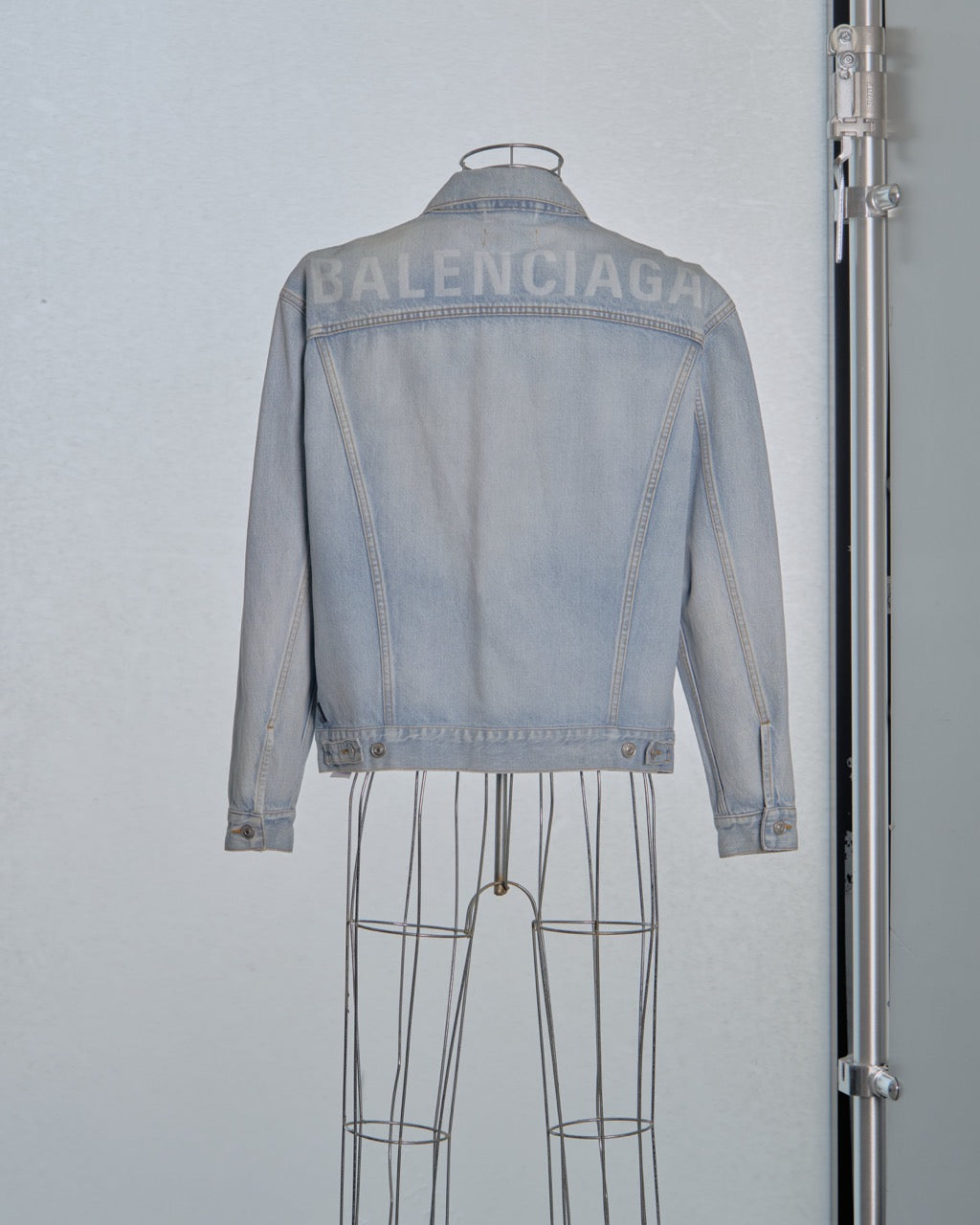 Light blue denim Balenciaga jacket on a mannequin against a gray background with Balenciaga branding.