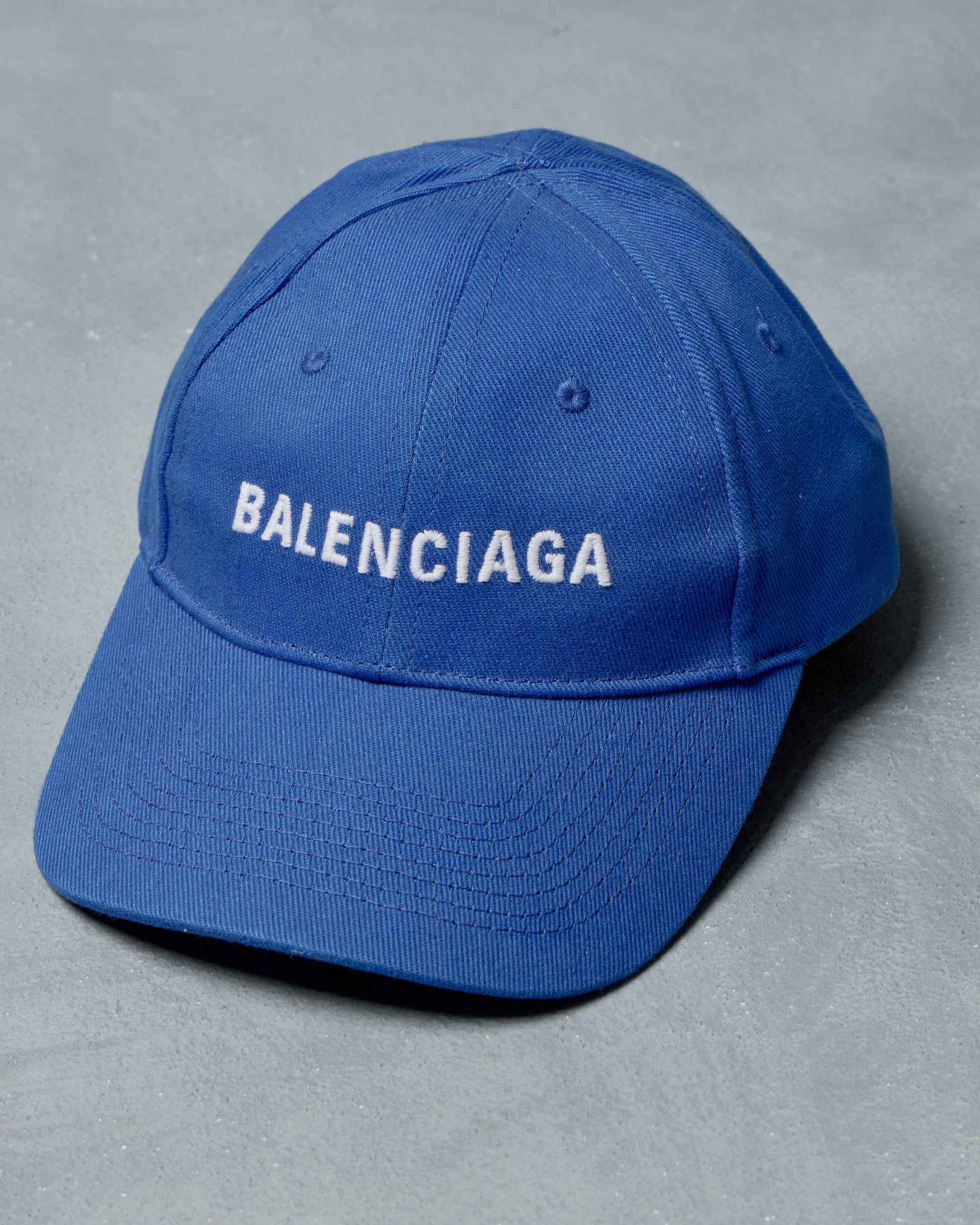 Blue cap with 'BALENCIAGA' logo on a gray background