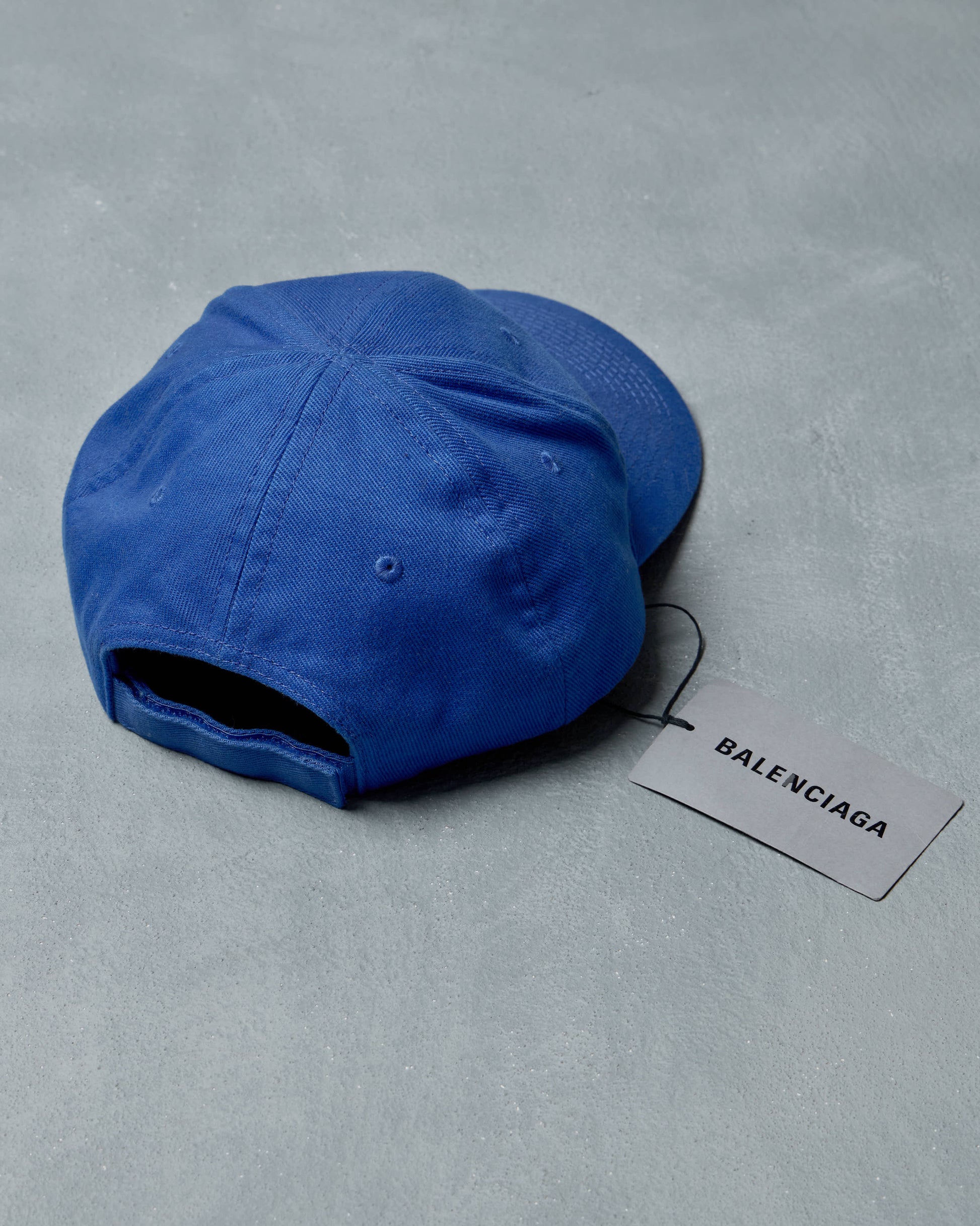 Blue cap with Balenciaga tag on a gray background