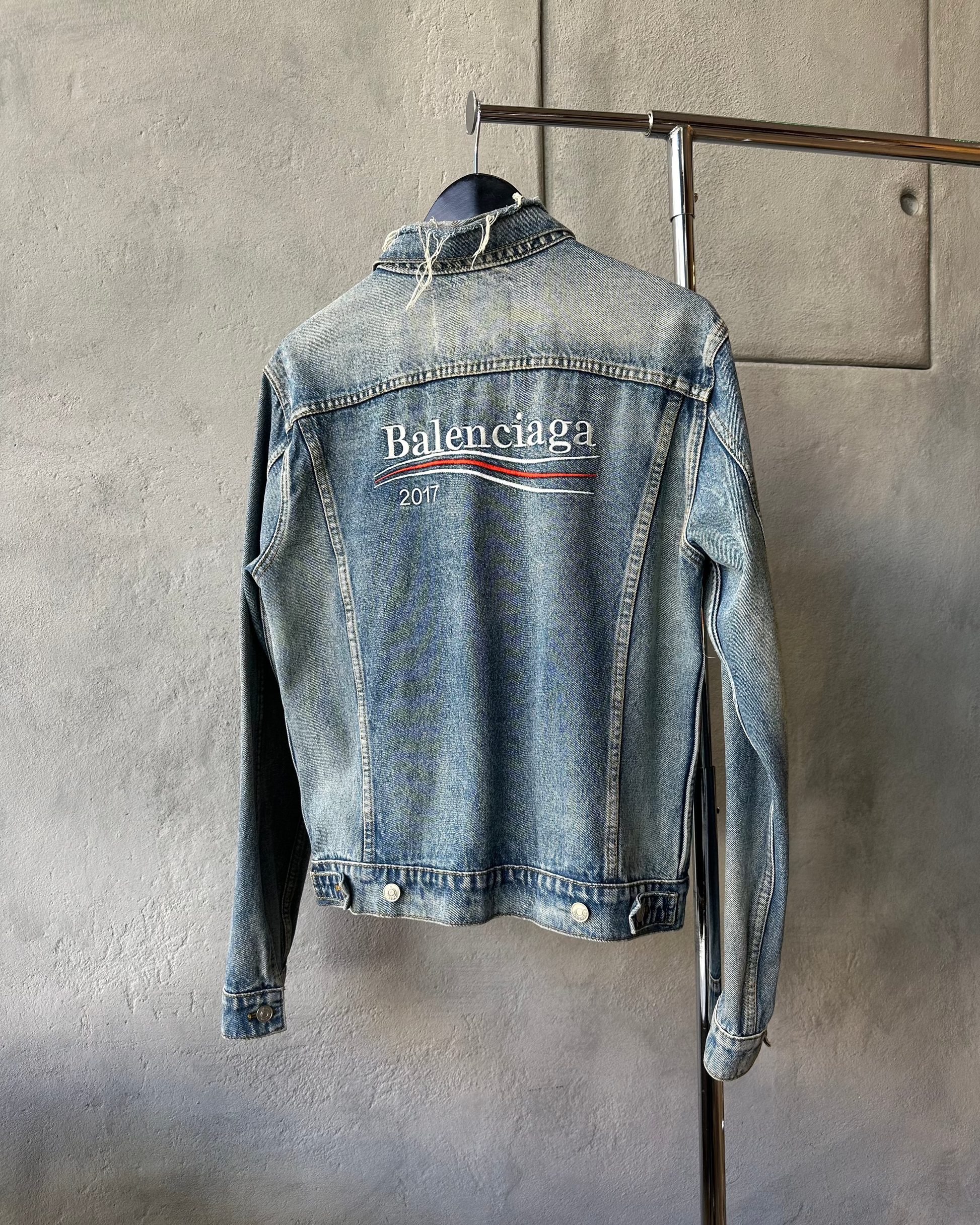 Blue denim jacket with Balenciaga logo on a gray background