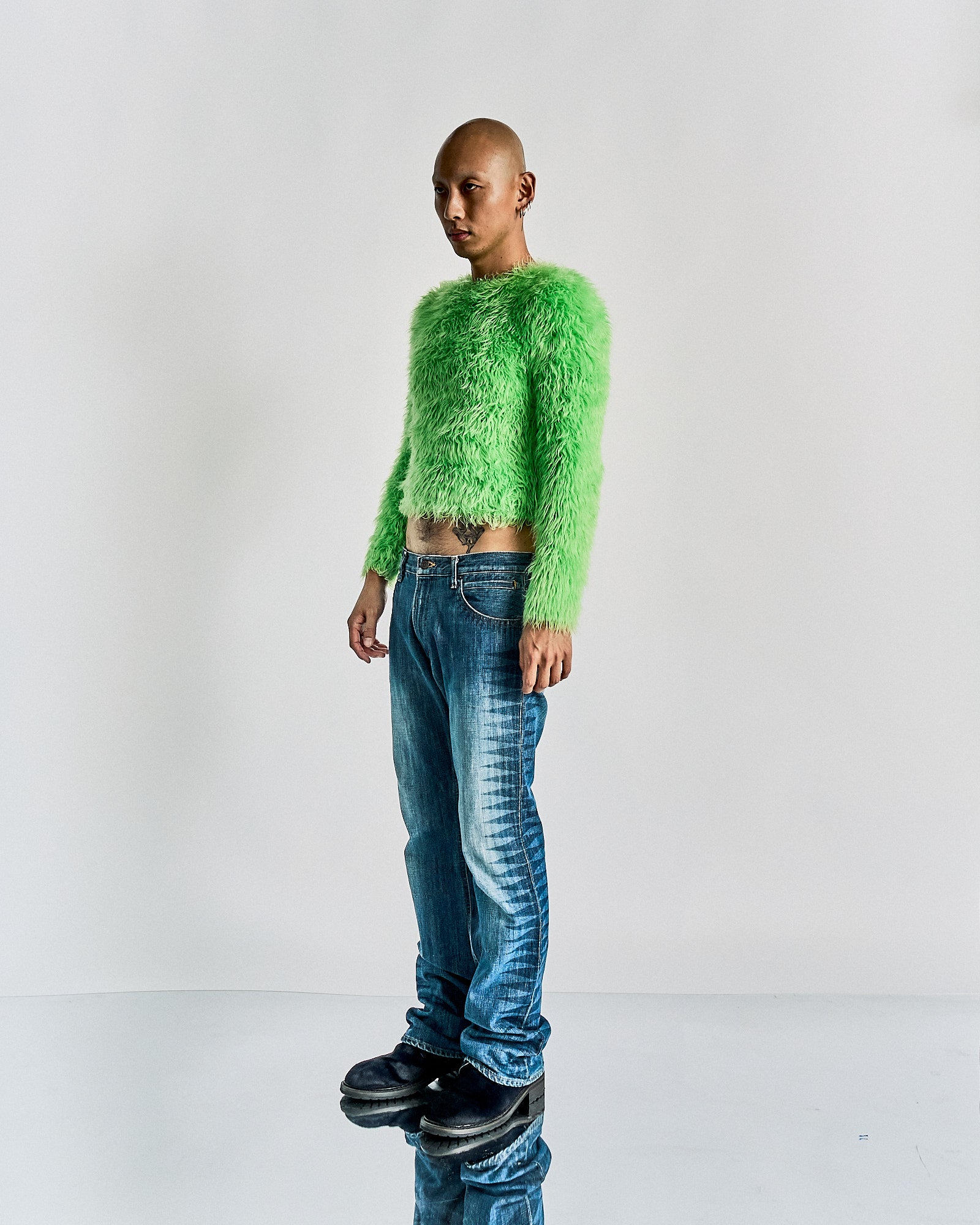 Person wearing a bright green fluffy Balenciaga sweater and blue jeans on a white background