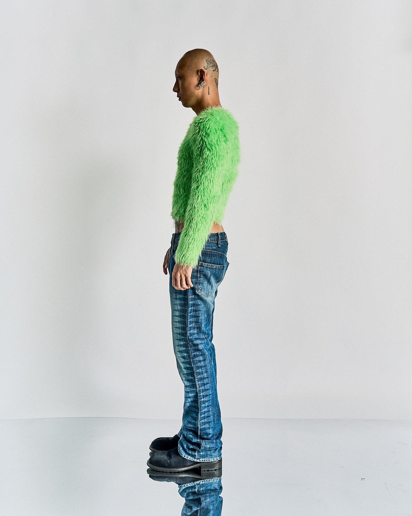 Person wearing a bright green fuzzy Balenciaga sweater and blue jeans on a white background
