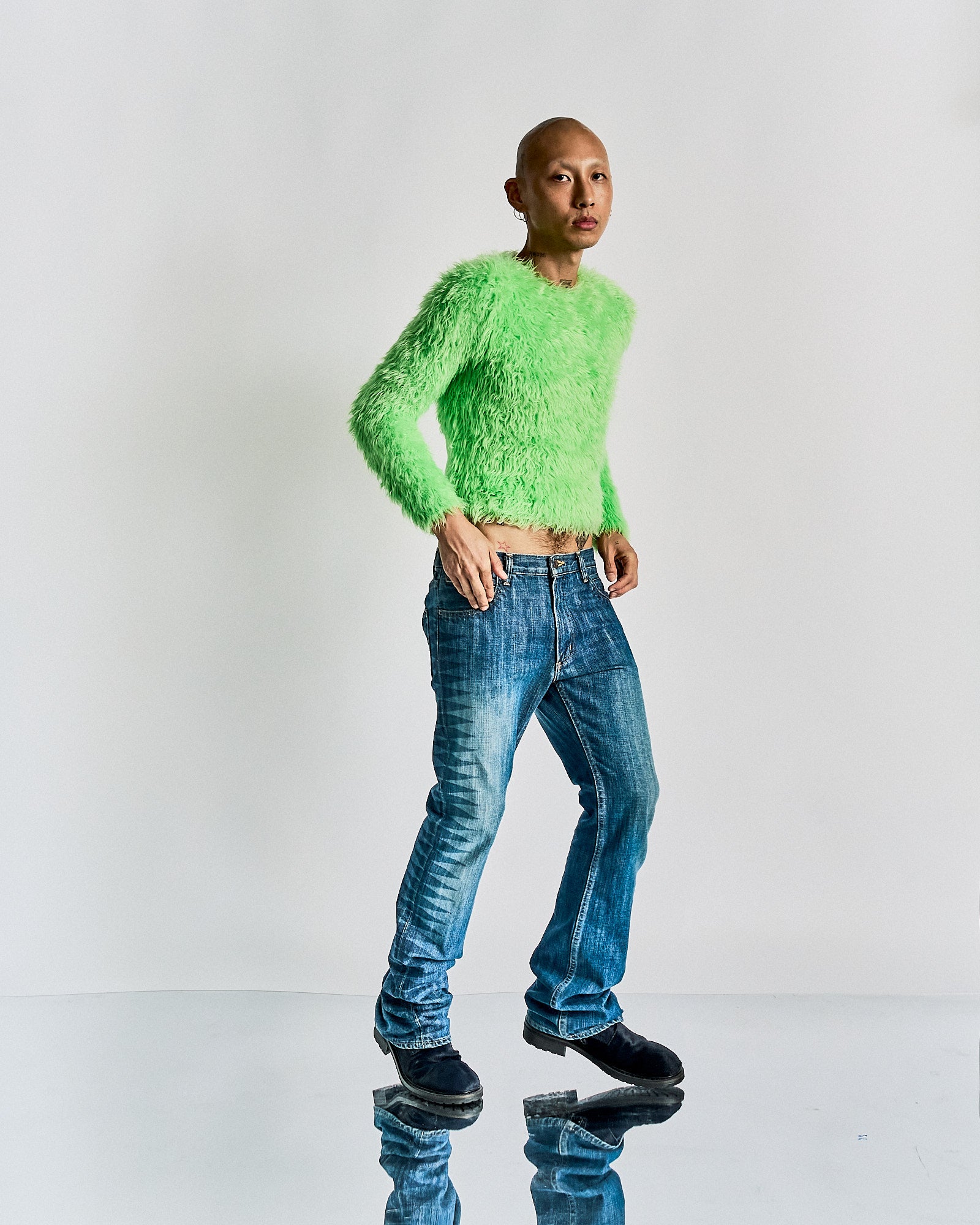 Person wearing a bright green fuzzy Balenciaga sweater and blue jeans on a white background