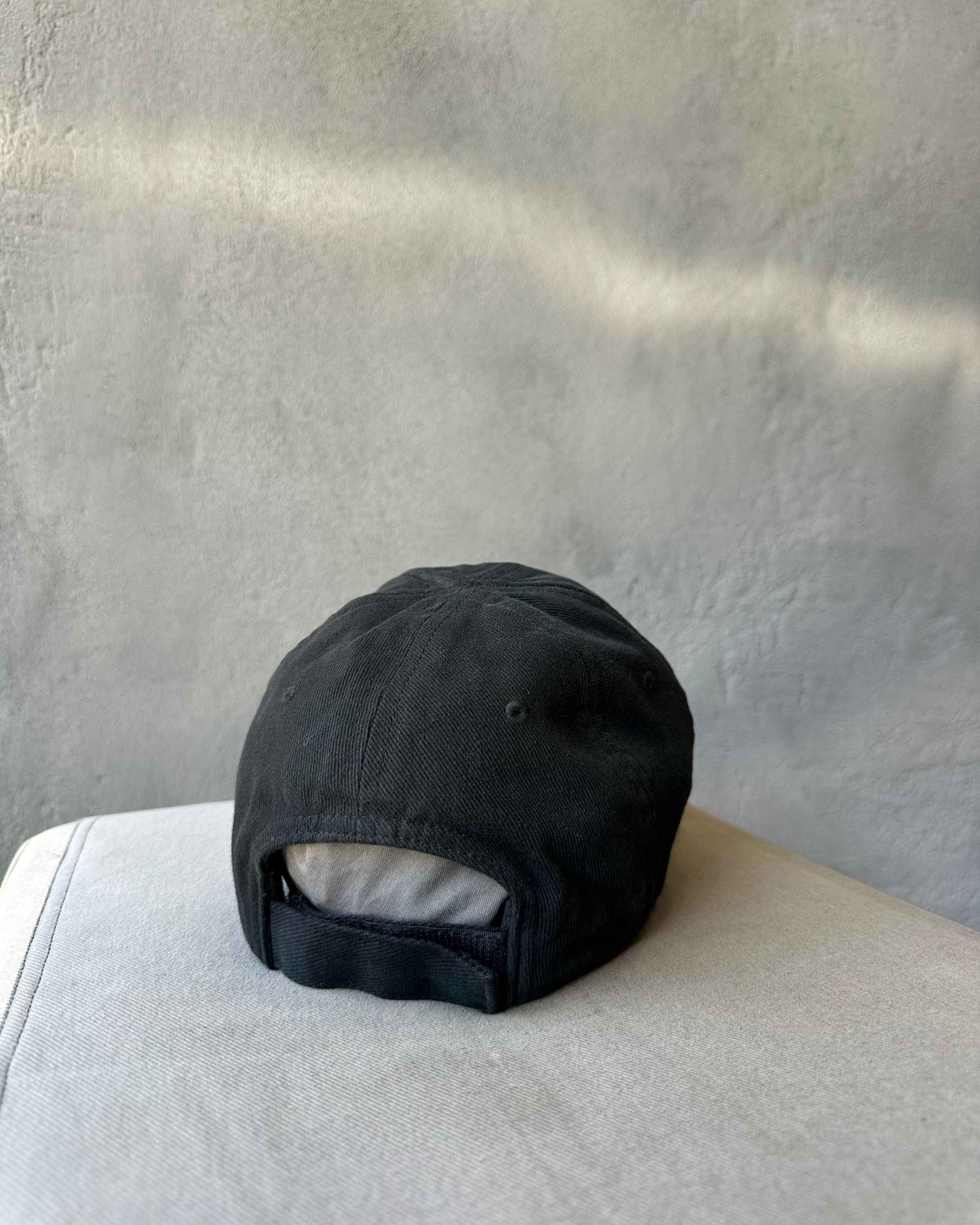 Black Balenciaga cap on a light gray surface with a neutral background