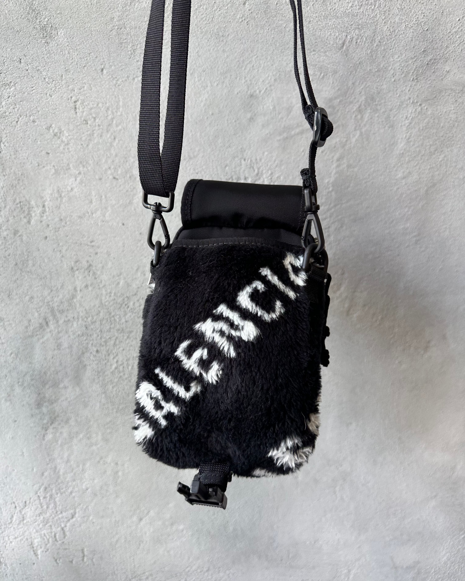 Black furry mini bag with 'Balenciaga' branding on a light gray background
