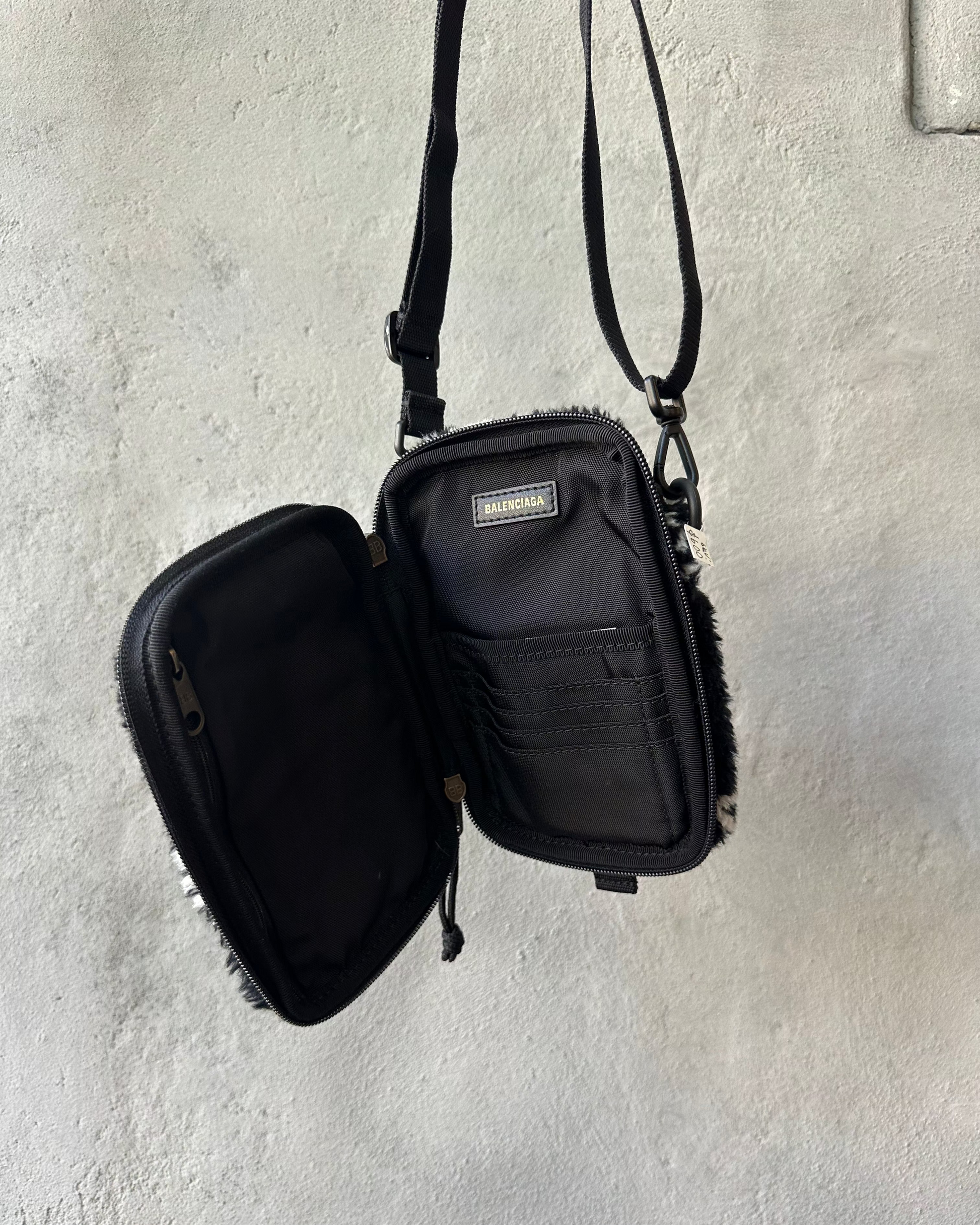 Black Balenciaga mini crossbody bag with open compartment on a light gray background