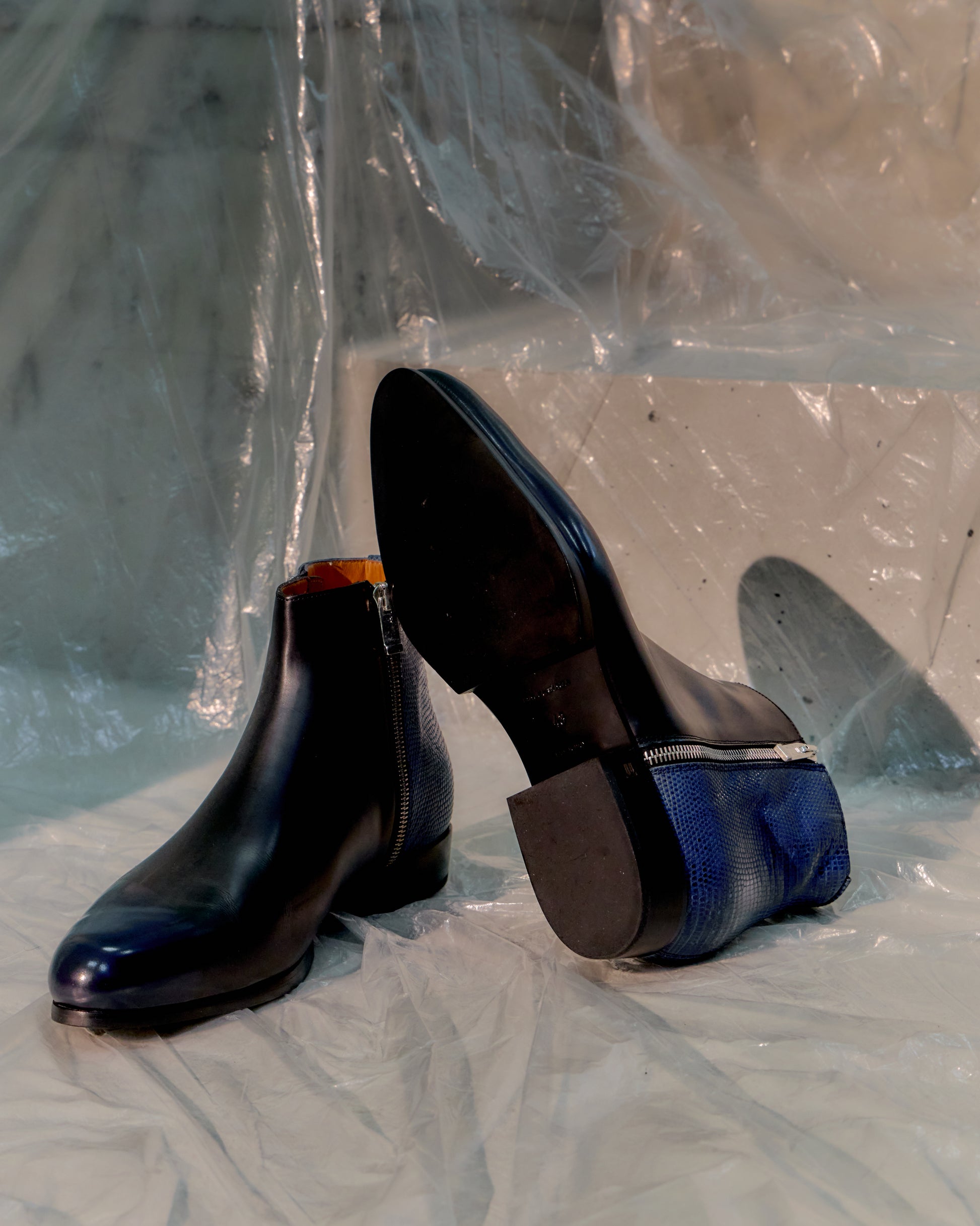 Pair of black and blue Balenciaga shoes on a reflective surface