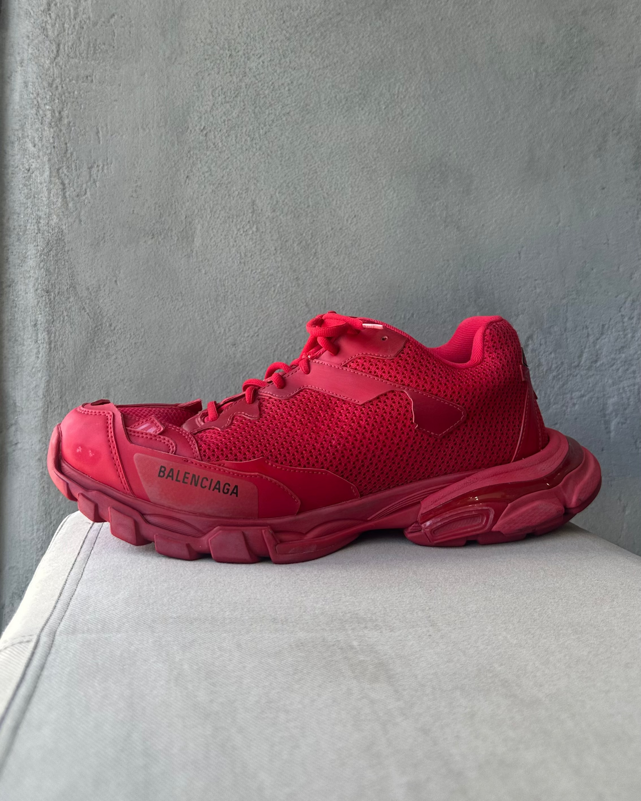 Red Balenciaga sneaker on a light gray surface with a neutral background