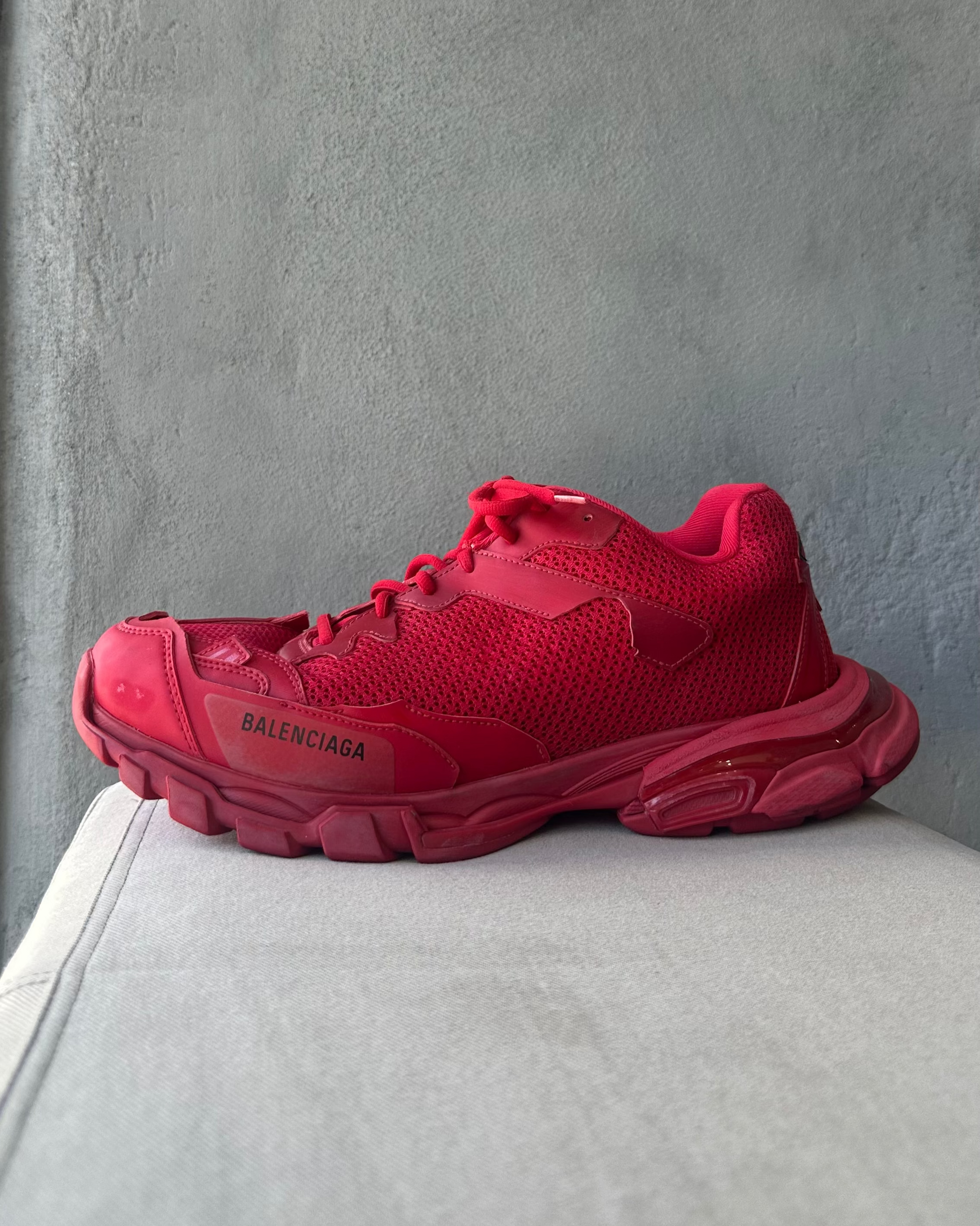 Red Balenciaga sneaker on a light gray surface with a neutral background