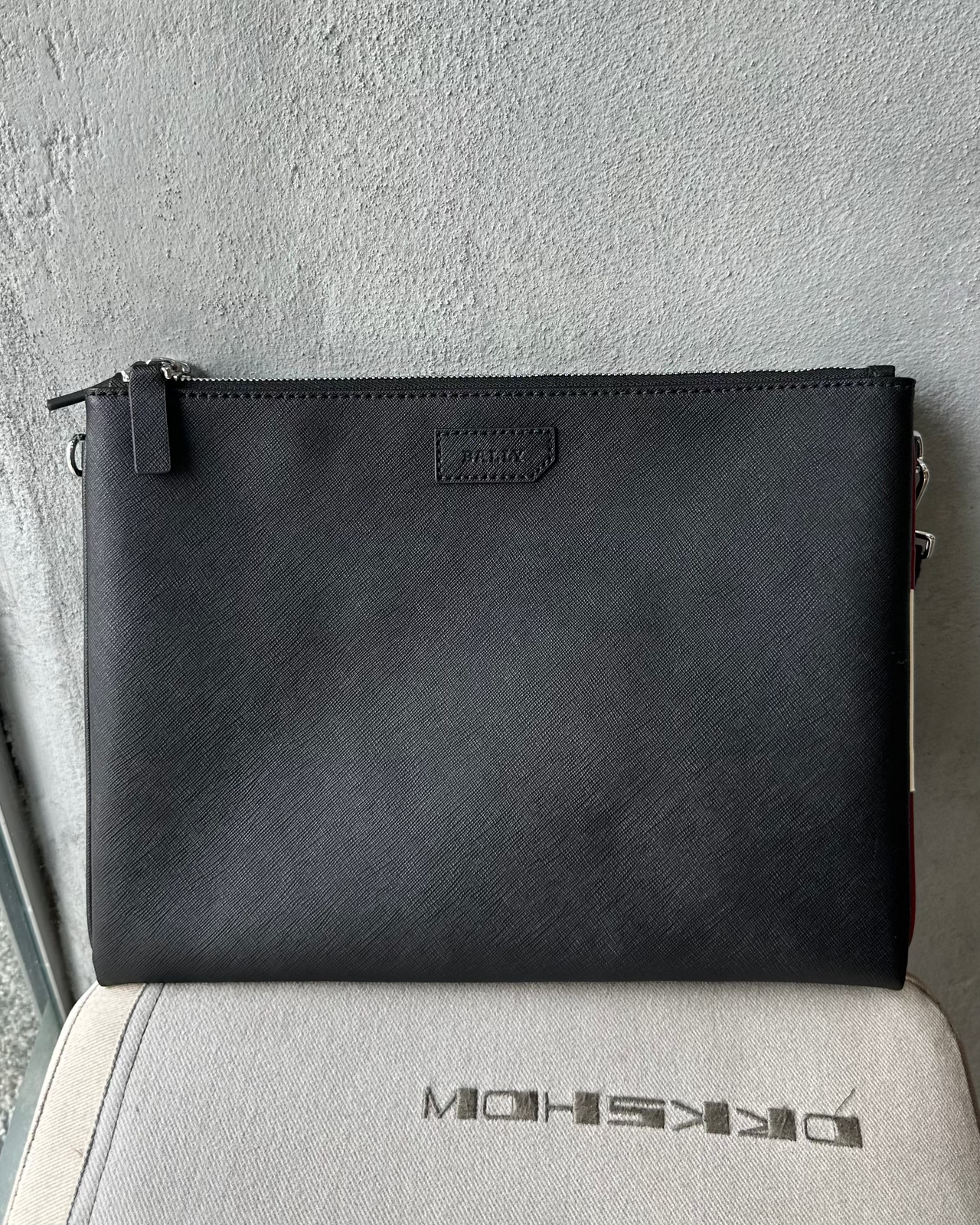 Black Bally clutch bag on a textured surface