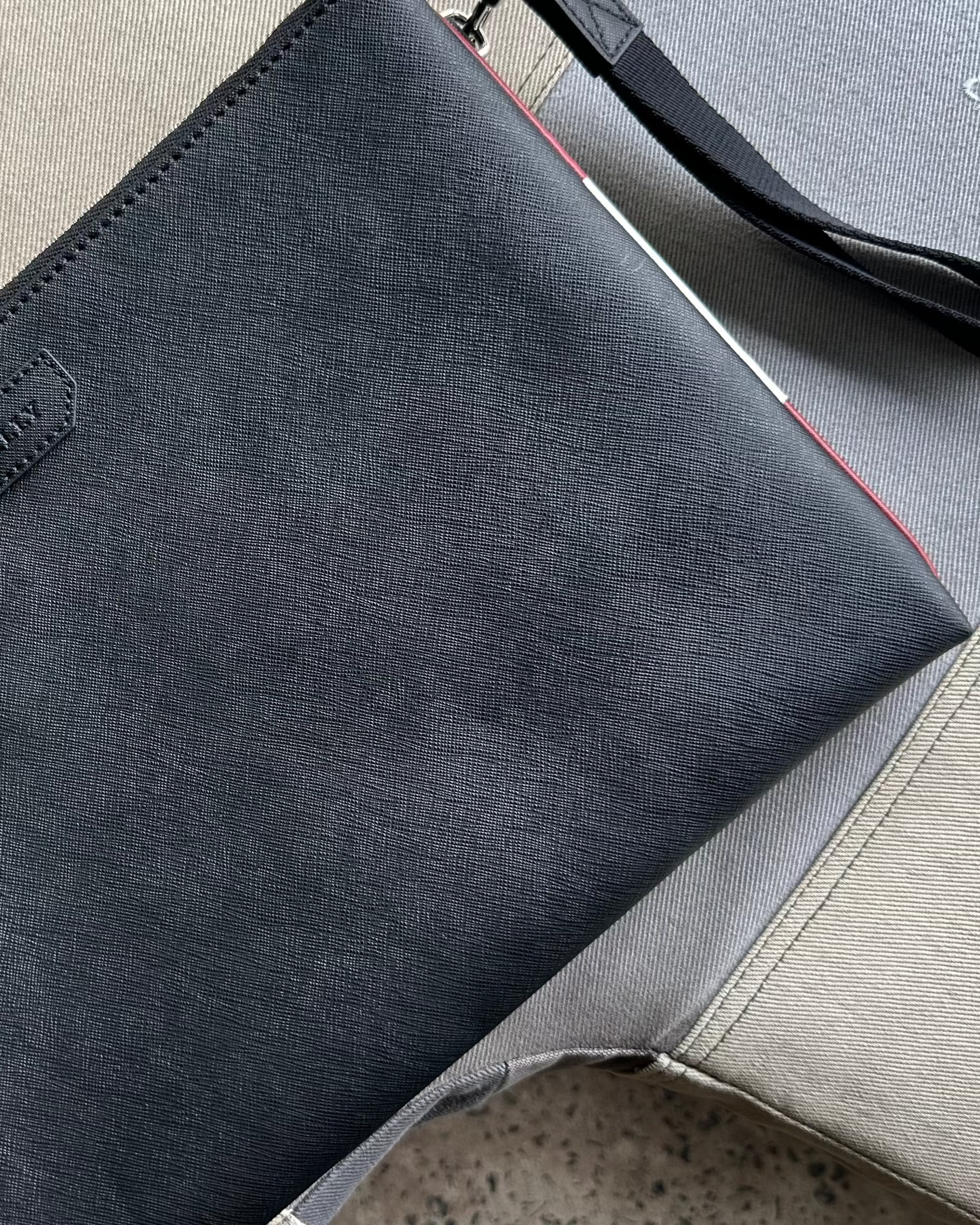 Black Bally leather clutch bag on a textured surface