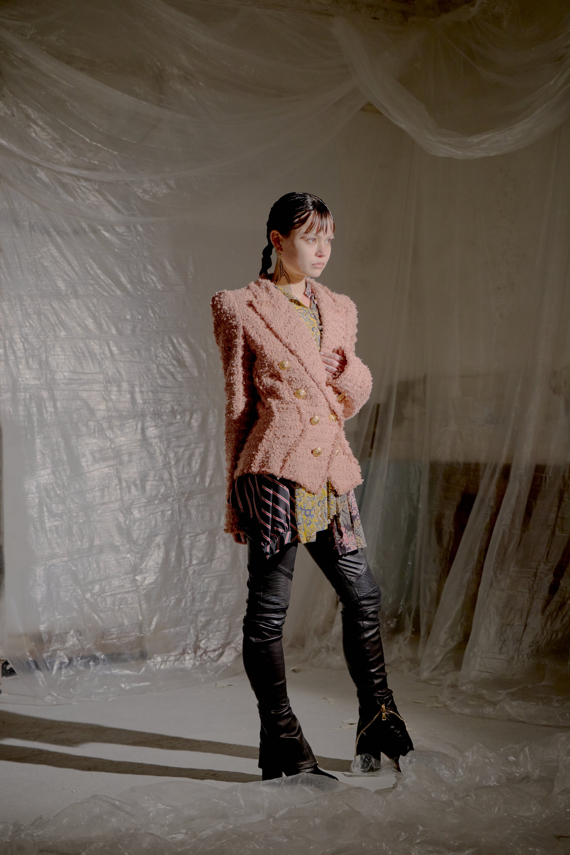 Person wearing a pink textured Balmain jacket in a minimalistic setting with draped fabric.