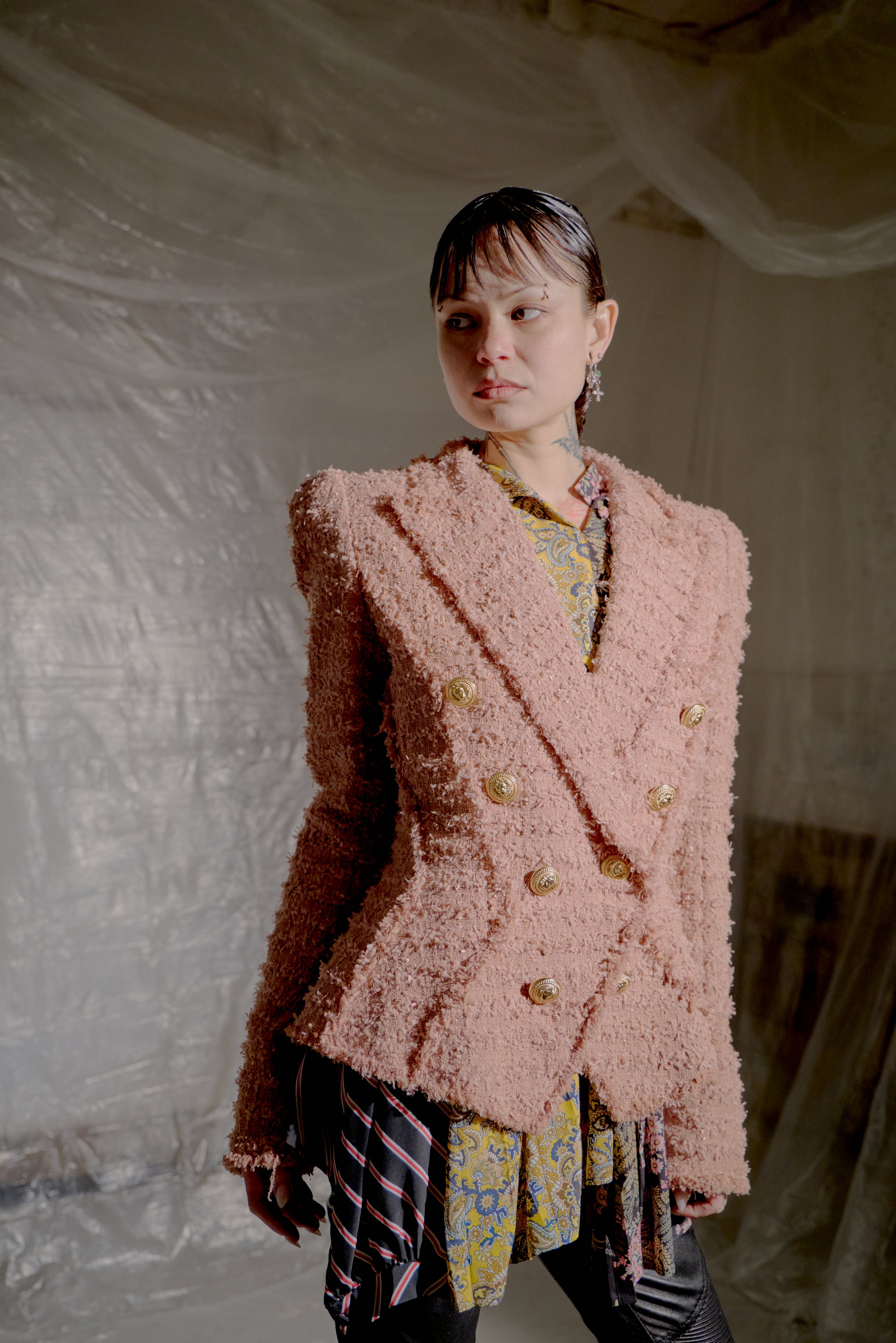 Person wearing a pink textured Balmain tweed jacket with a neutral background