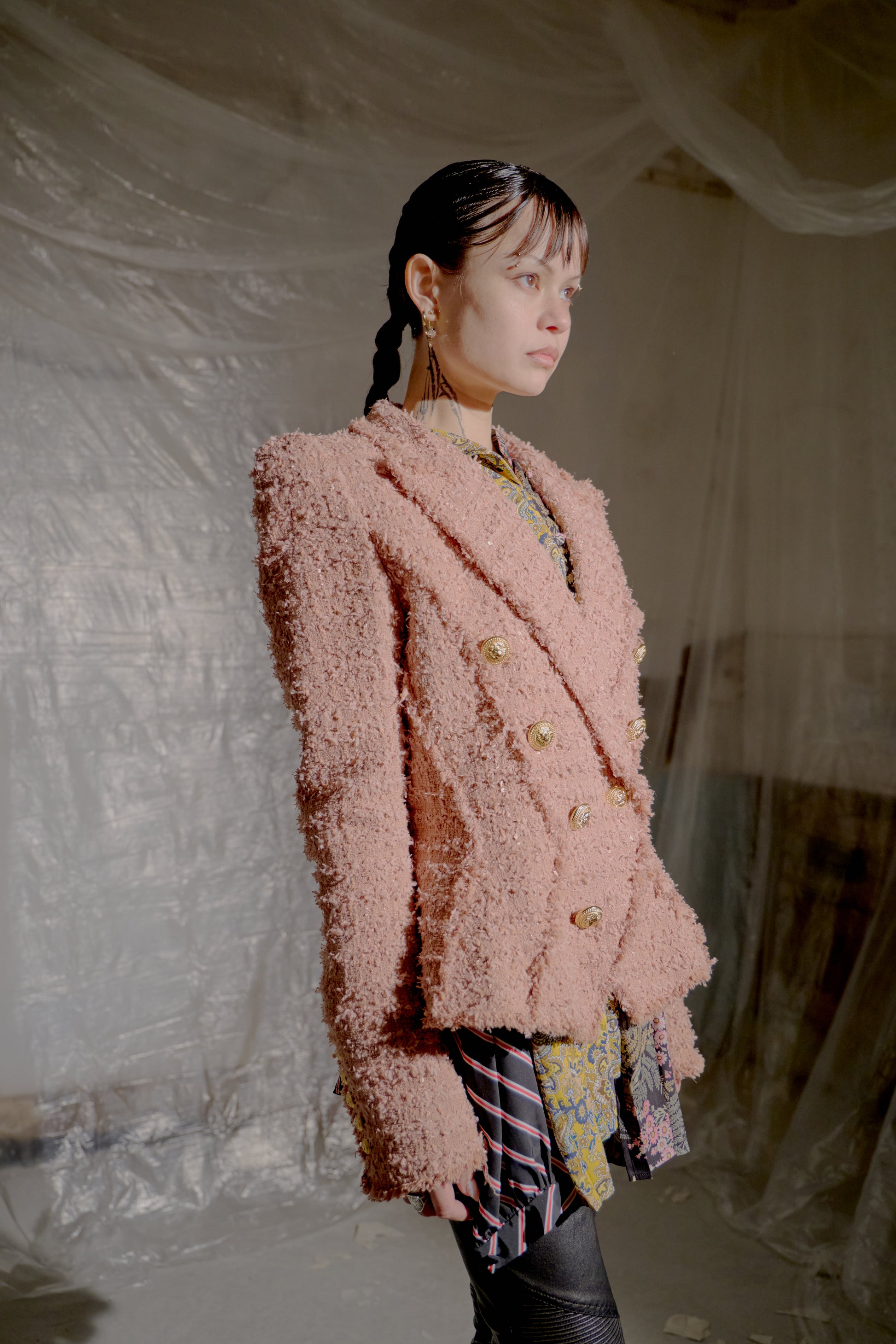 Person wearing a pink textured Balmain jacket in a minimal indoor setting