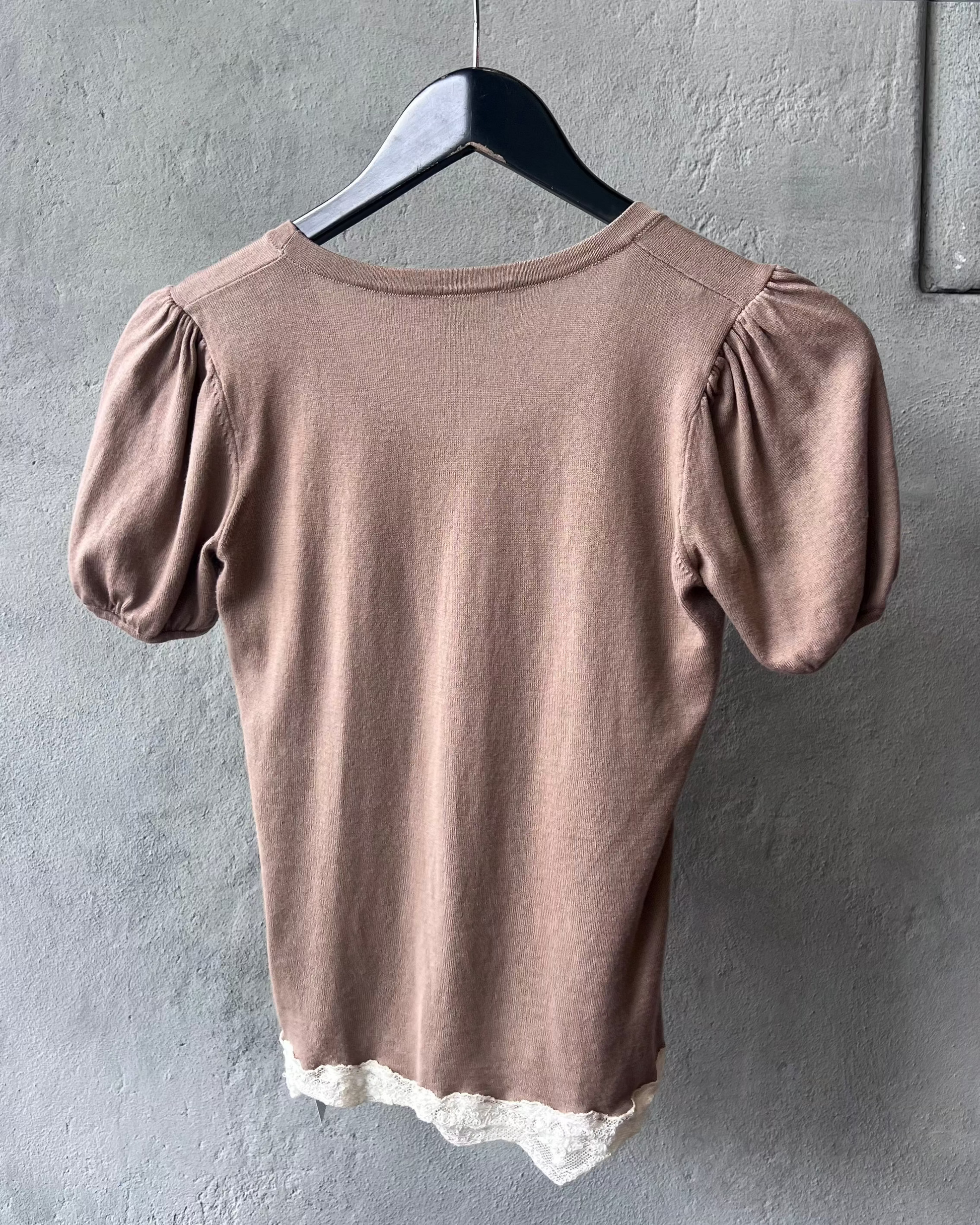 Brown Blumarine blouse with lace trim on a hanger against a gray wall