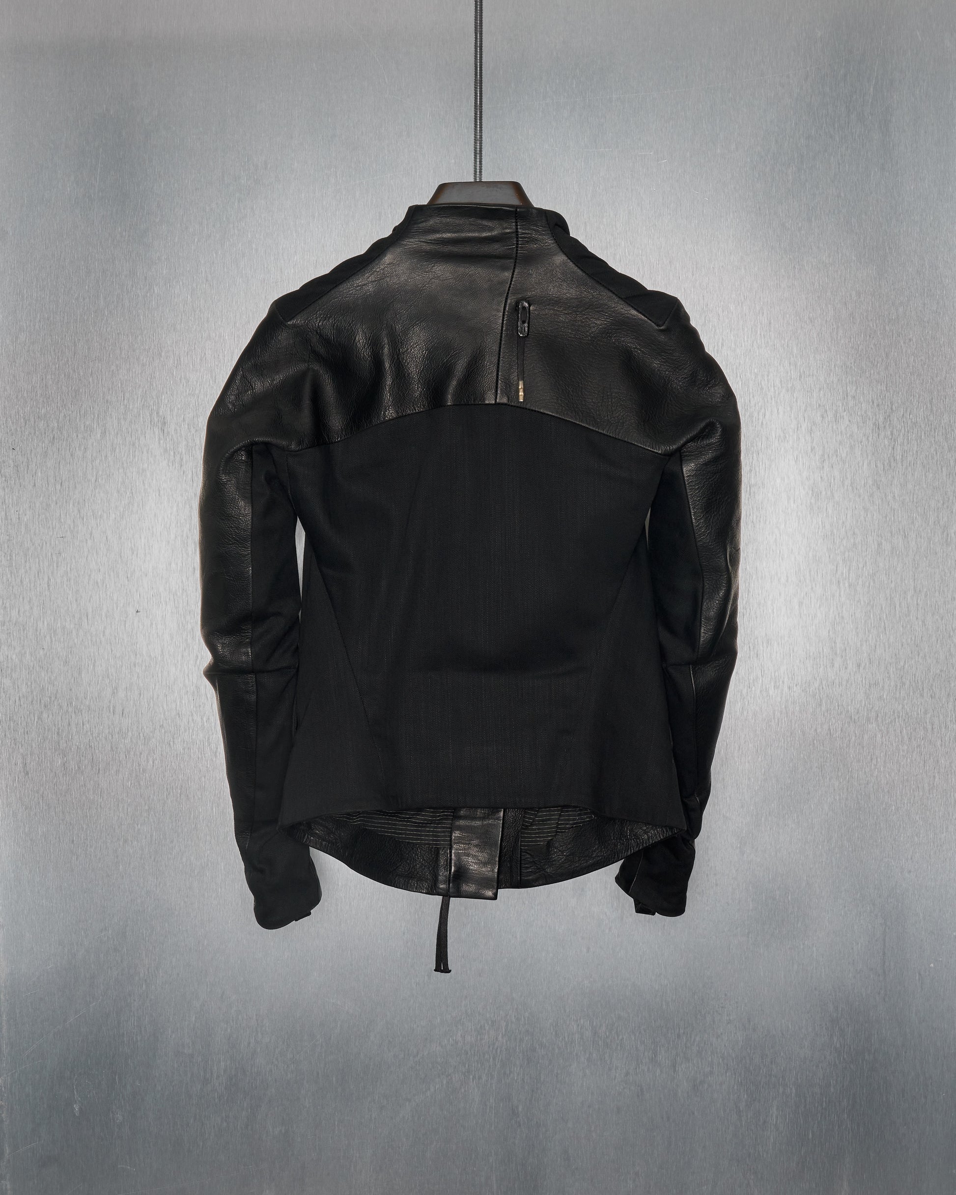 Black leather Boris Bidjan Saberi  jacket, displayed from the back against a grey textured background. The design is sleek and modern, featuring a zipper near the collar.
