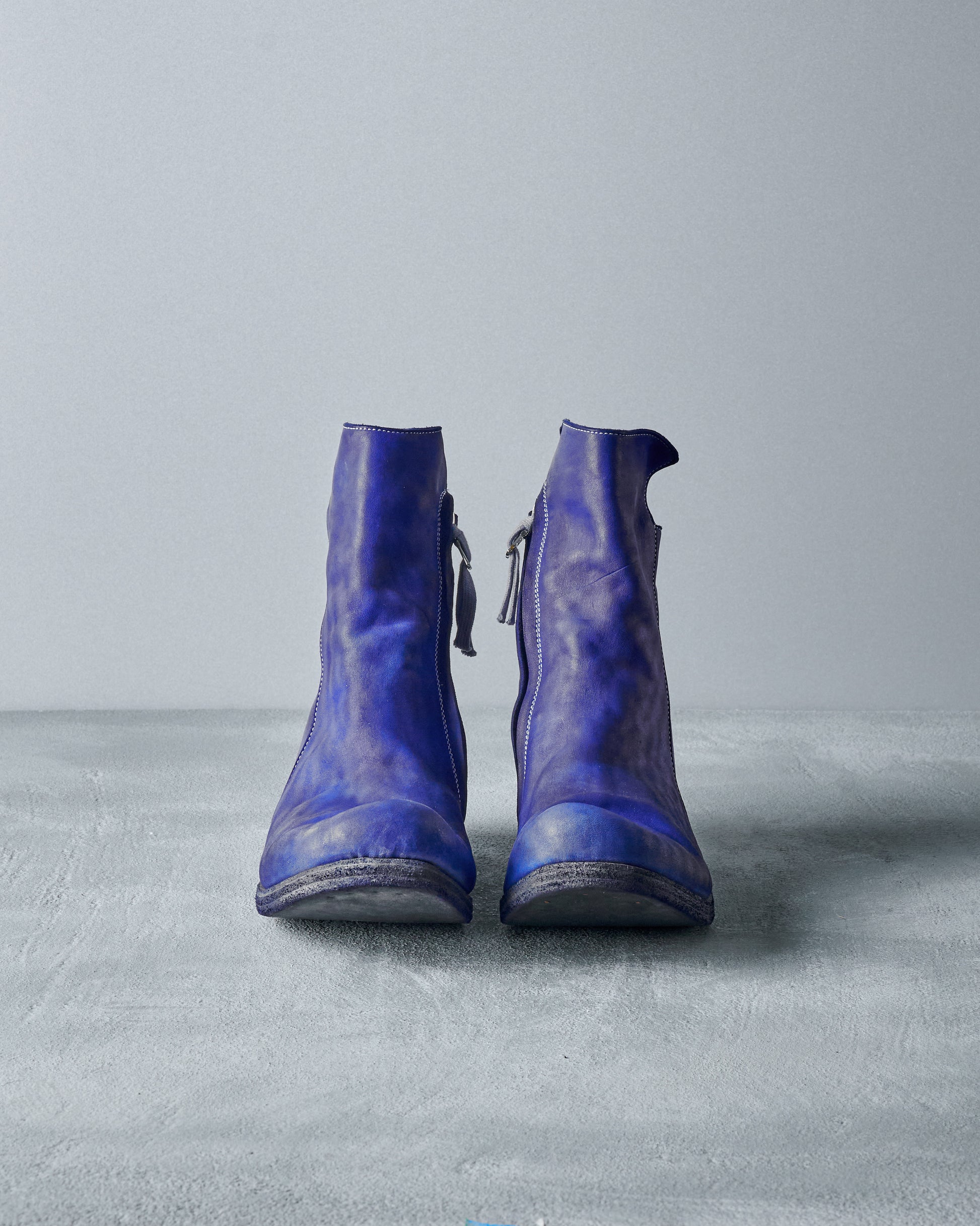 A pair of vibrant blue Boris Bidjan Saberi leather boots with visible creases is centred against a light grey background.