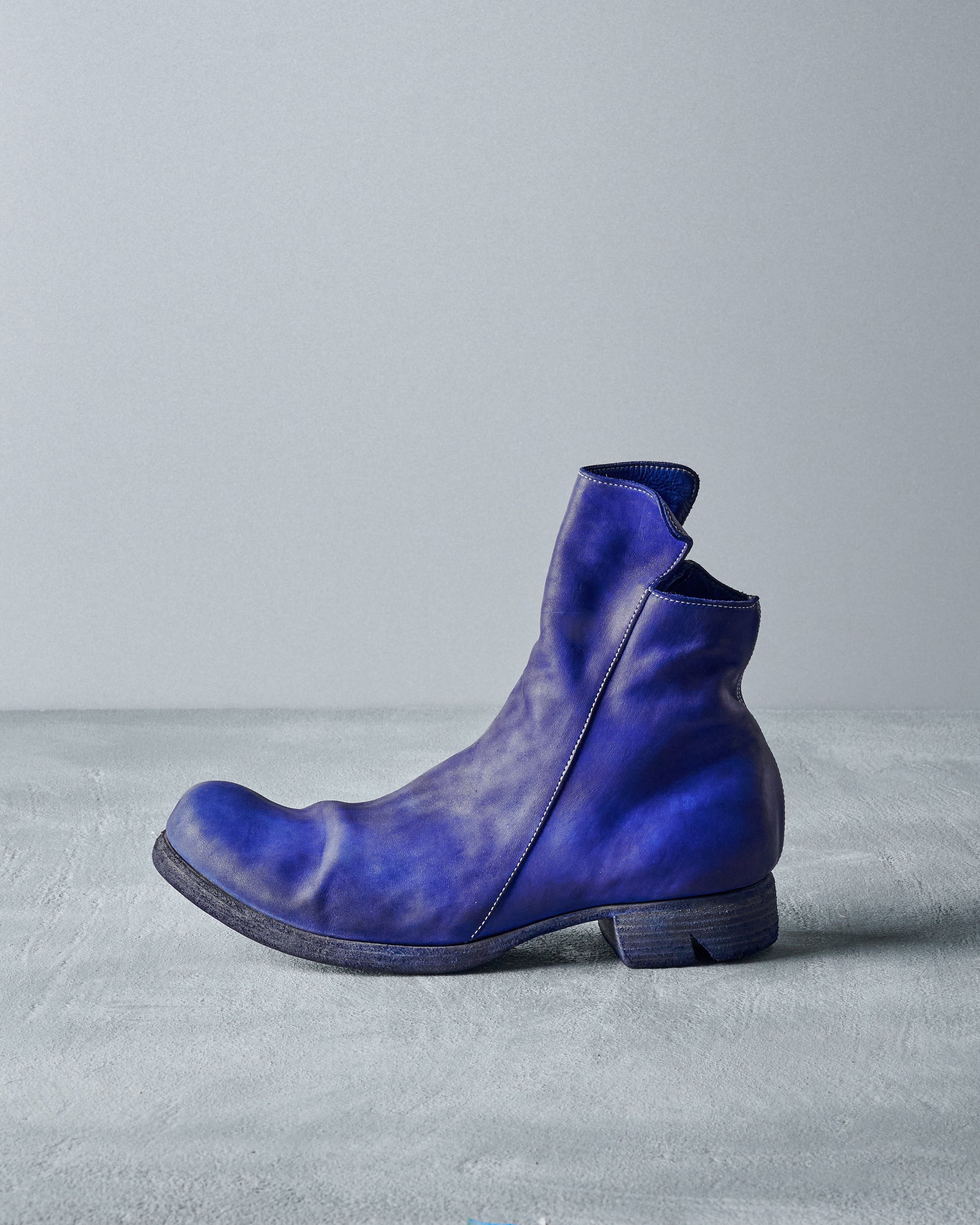 A single blue leather Boris Bidjan Saberi boot sits on a textured grey surface against a plain backdrop.
