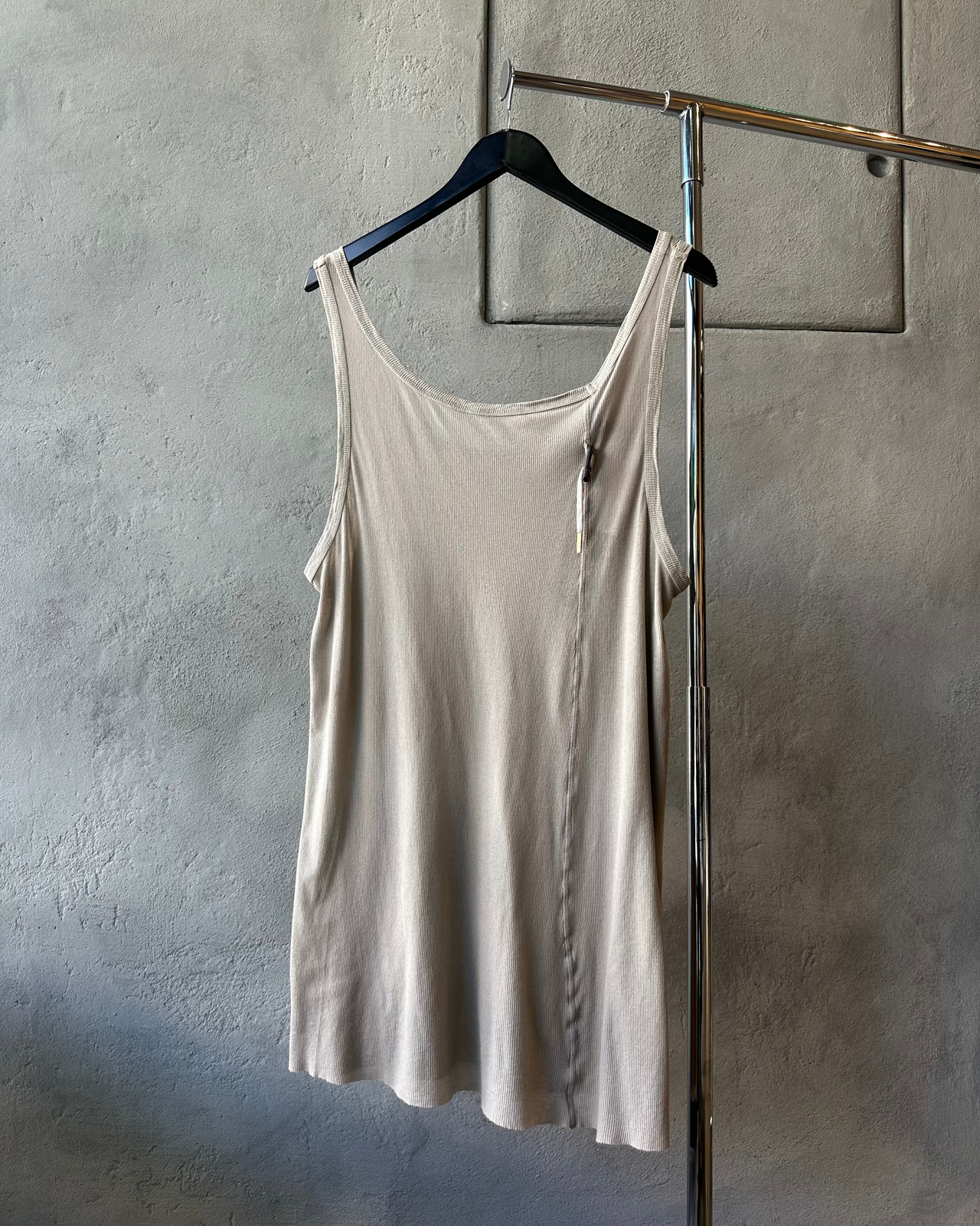 Beige Boris Bidjan Saberi tank top hanging on a rack against a gray wall.