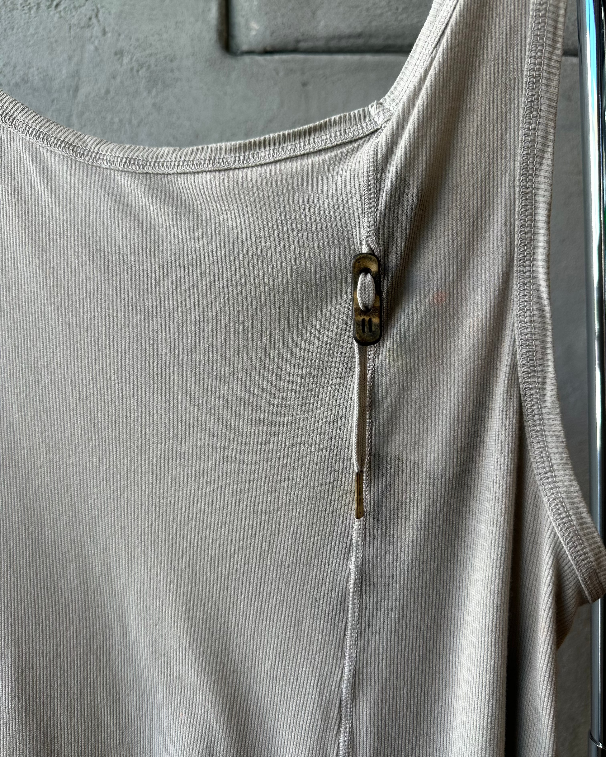 Close-up of a light gray Boris Bidjan Saberi ribbed tank top with a zipper on a textured surface.