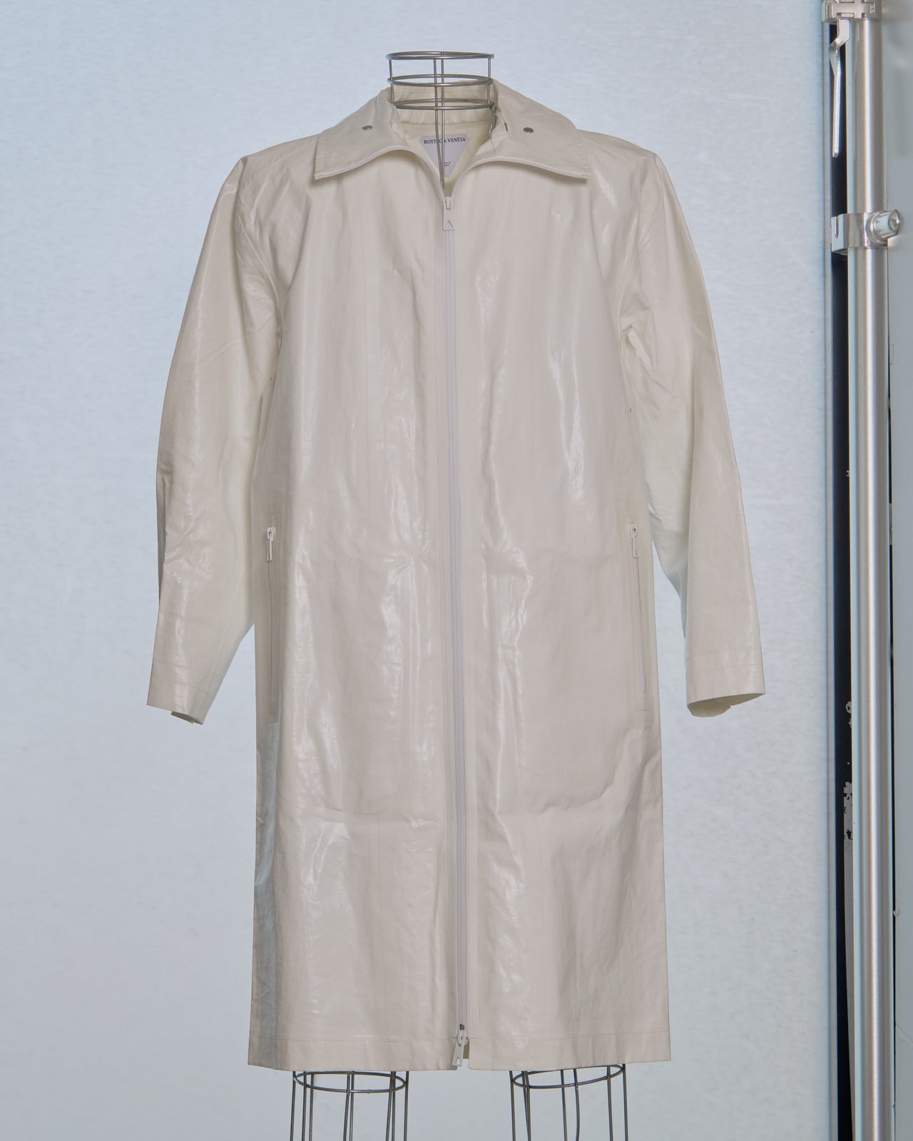White Bottega Veneta trench coat on a mannequin against a light gray background