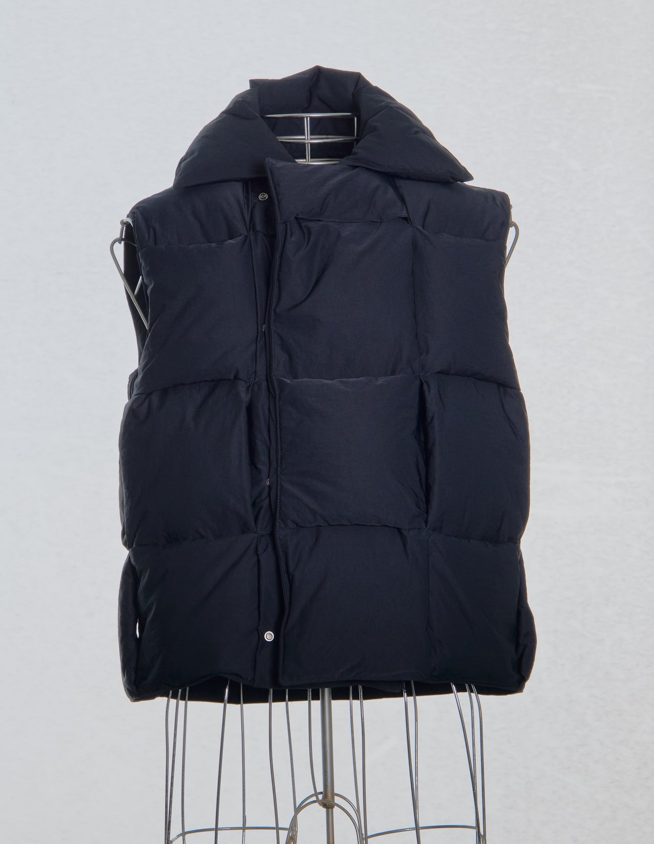 Black Bottega Veneta puffer vest on a mannequin against a light gray background