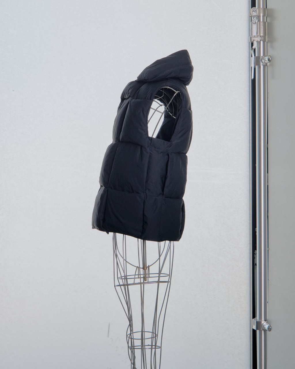 Black Bottega Veneta puffer vest on a mannequin against a white background